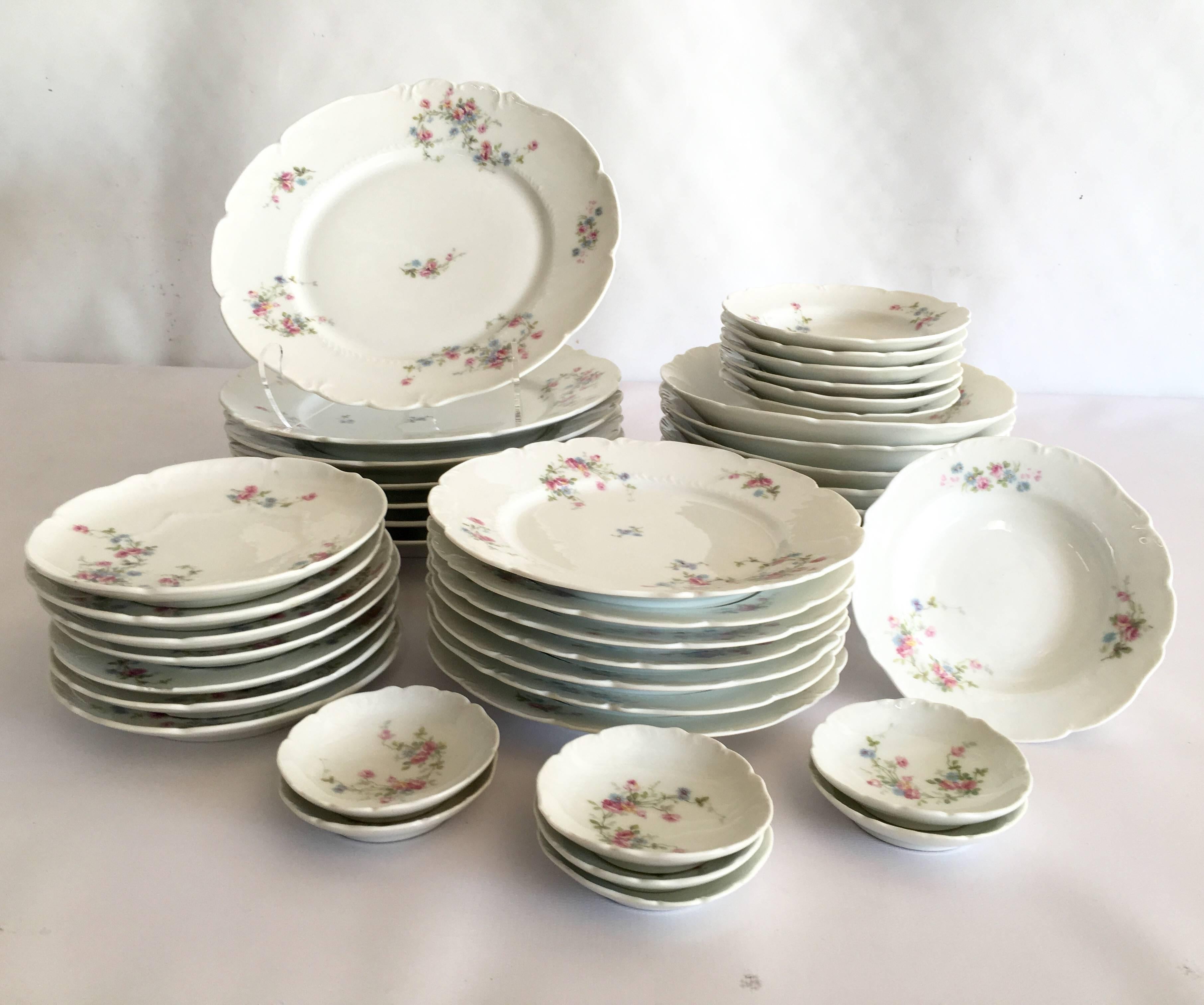 Rare 42 piece set of Early 20th Century L.R.L Limoges porcelain dinnerware Pattern features a white ground with pink, green and violet roses and a  scalloped edge. Set includes seven six piece place settings of  dinner plates, salad/dessert plates,