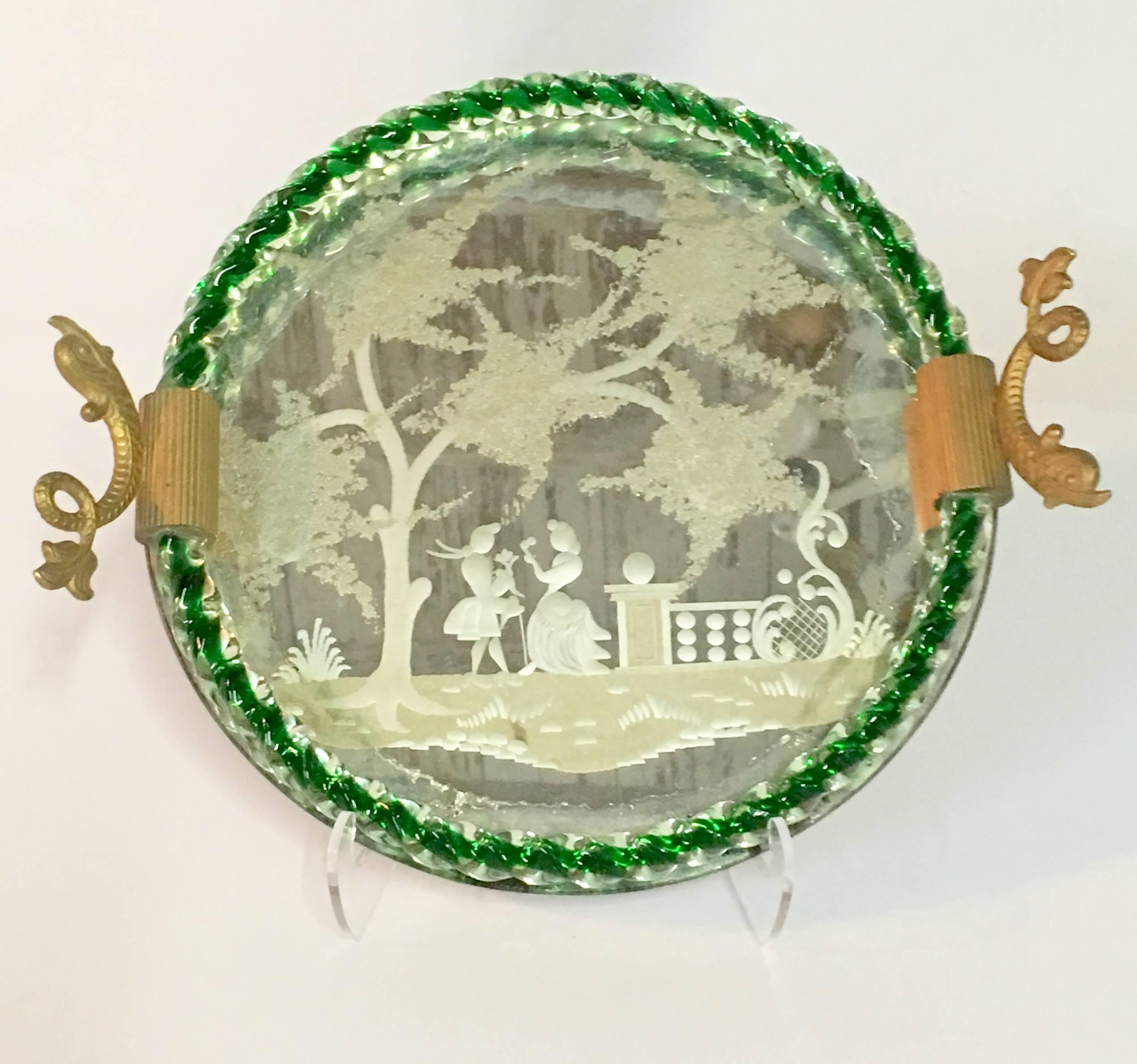 Vintage Italian Venetian and Murano glass, etched mirror gilt brass dolphin handle round tray. This very special piece features a courting couple in a garden motif etched mirror with Murano clear and emerald green rope glass trim surround detail