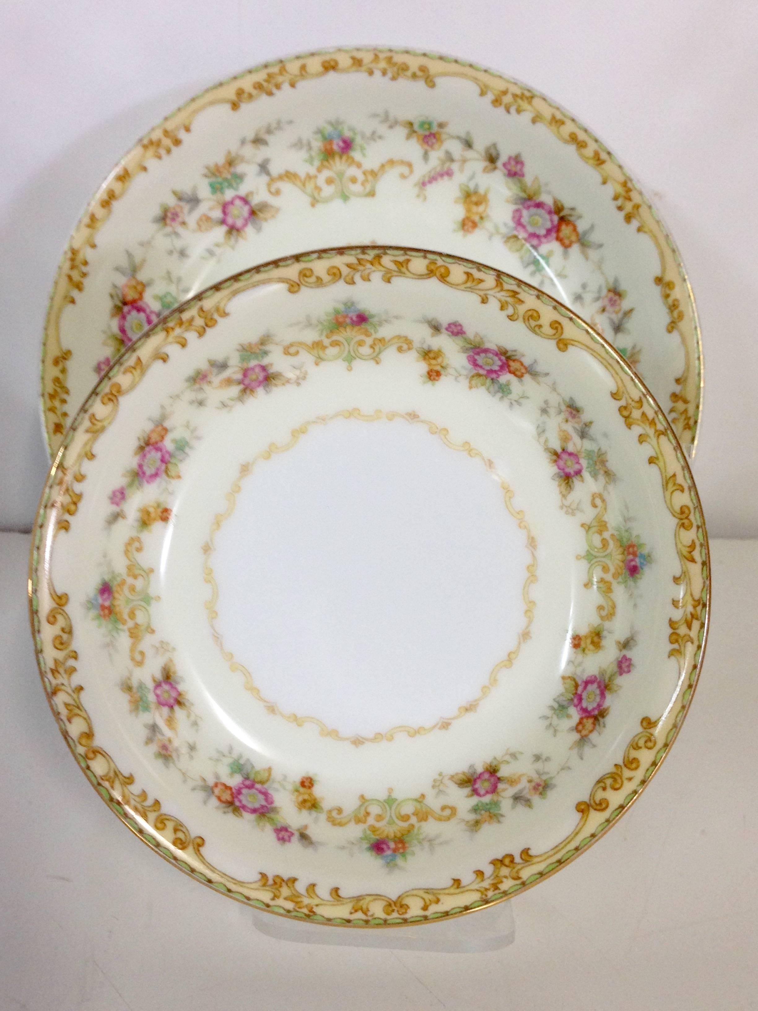 1930s set of nine Japanese Art Nouveau style white ground with pale yellow border and pink, blue and green flowers with gold scrolls pattern hand-painted 22-karat gold rim detail bowls. Set includes, three rim soup bowls and 6 fruit bowls, 1"