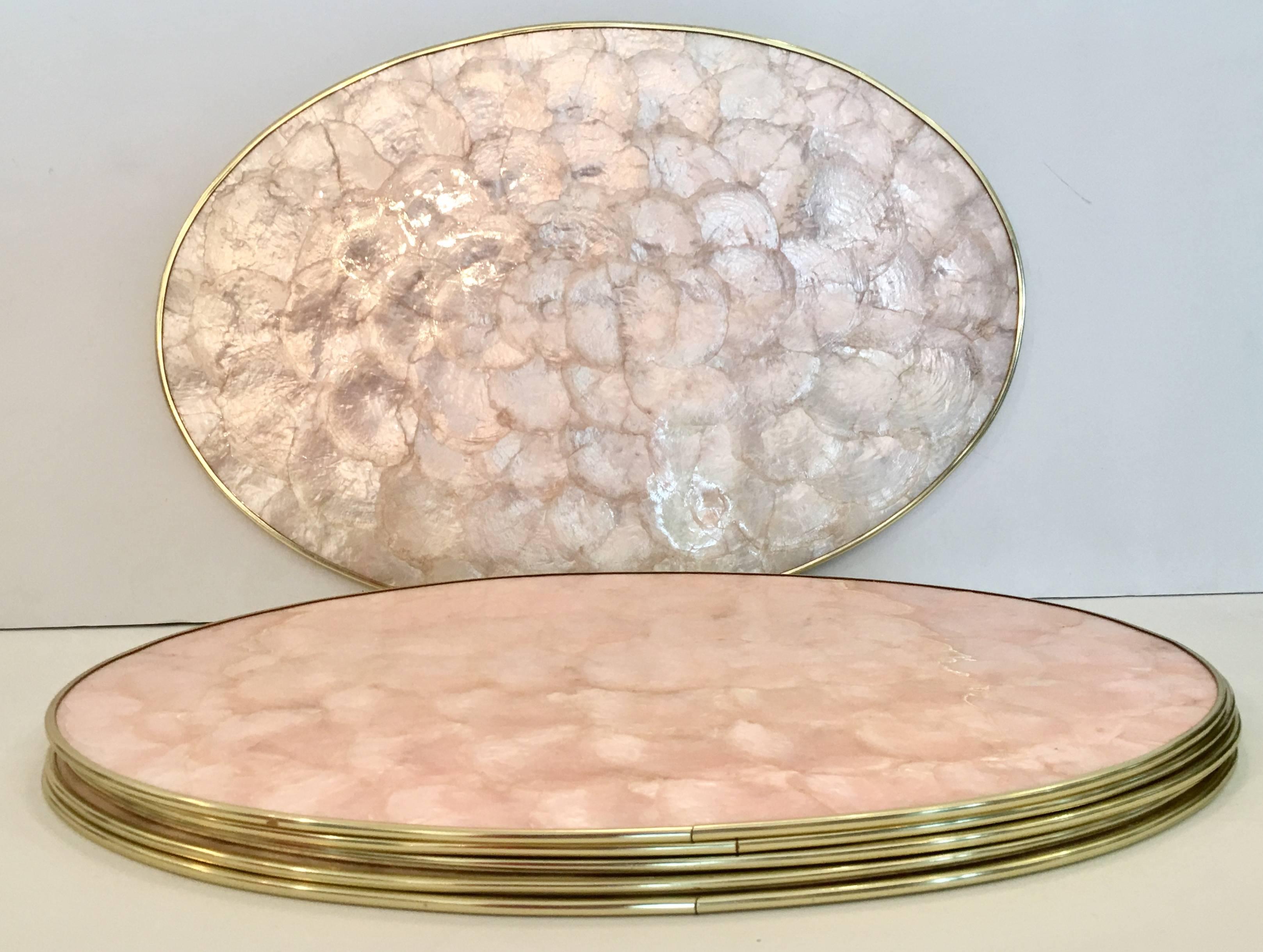 Set of six pink capiz shell mother-of-pearl with raised brass rim oval placemats.
Each placement is backed with cork and in excellent vintage condition.
