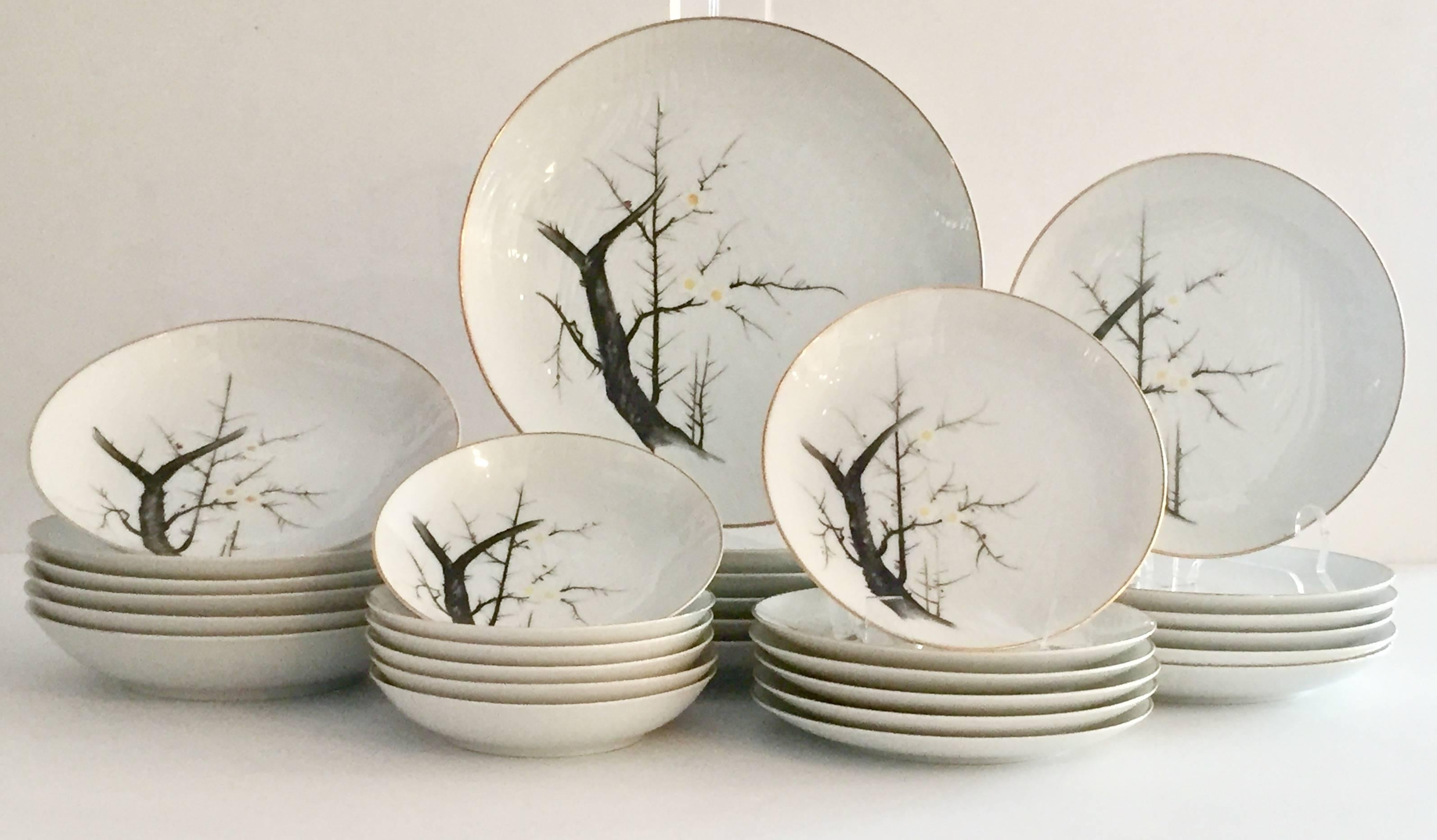 Set of 35 pieces Japanese porcelain "White Plum" with 22-karat gold detail. White faux bois textured ground with trees, birds and flowers rendered in black, white, yellow, teal and red. Set includes seven, five-piece place settings, seven