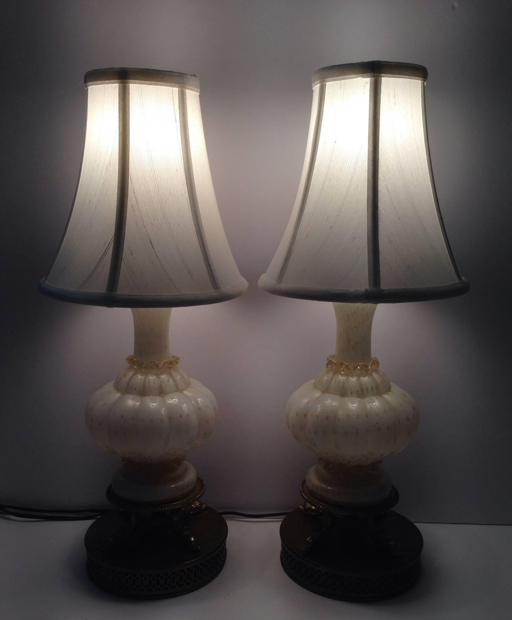 Antique and adorable pair of Italian white ribbed with 24-karat gold bullicante (controlled bubbles) and ribbon detail Murano glass lamps. Original brass bases. White silk shades are included.
Each lamp is 16" height from base to socket.