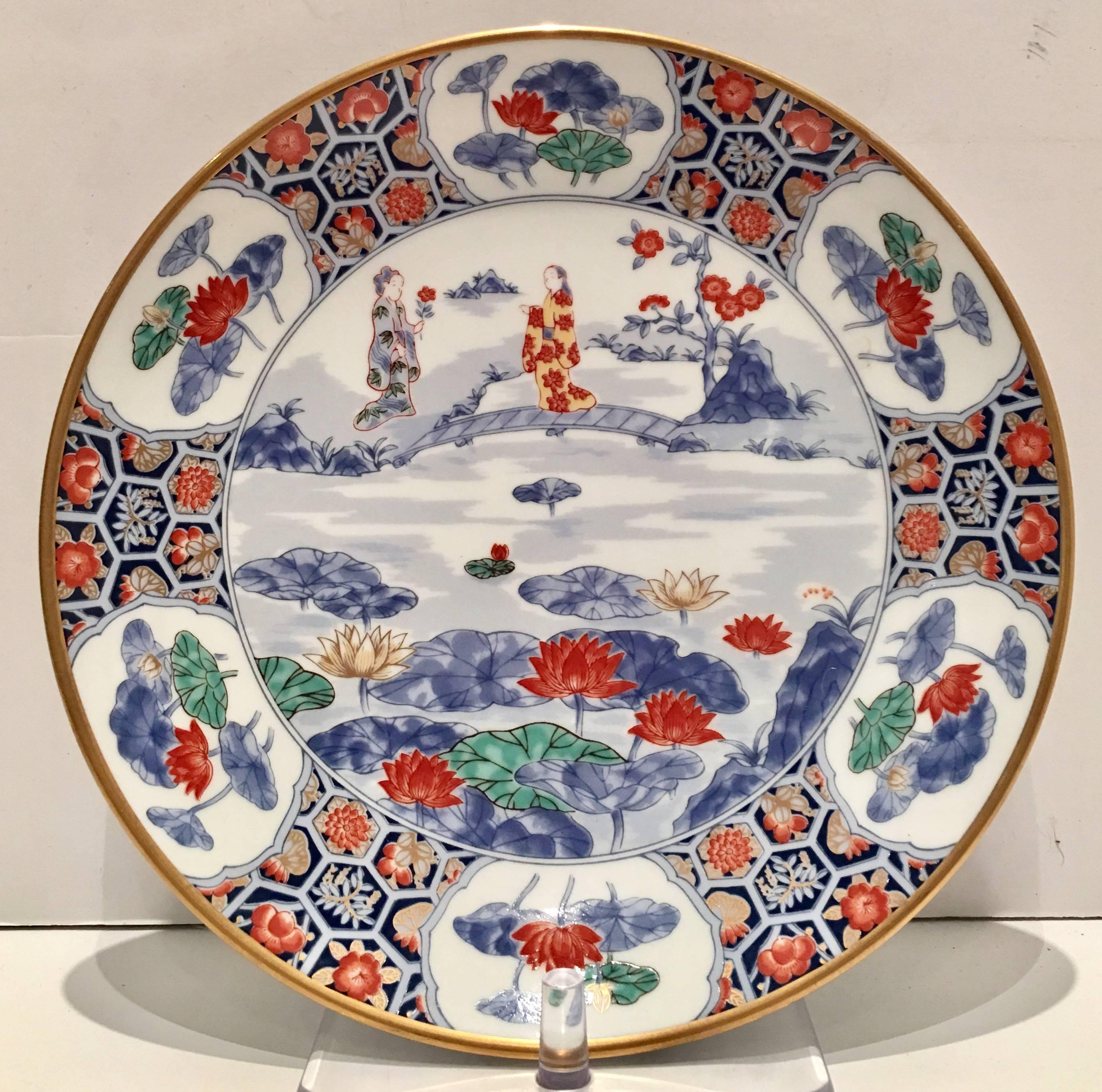 Midcentury unique set of Japanese porcelain with a gold rim geisha girl and cherry blossom motif hand painted plates.These Imari plates have a bright white ground and are decorated in gold, rust, blue, green and yellow with a 22K gold rim. Each