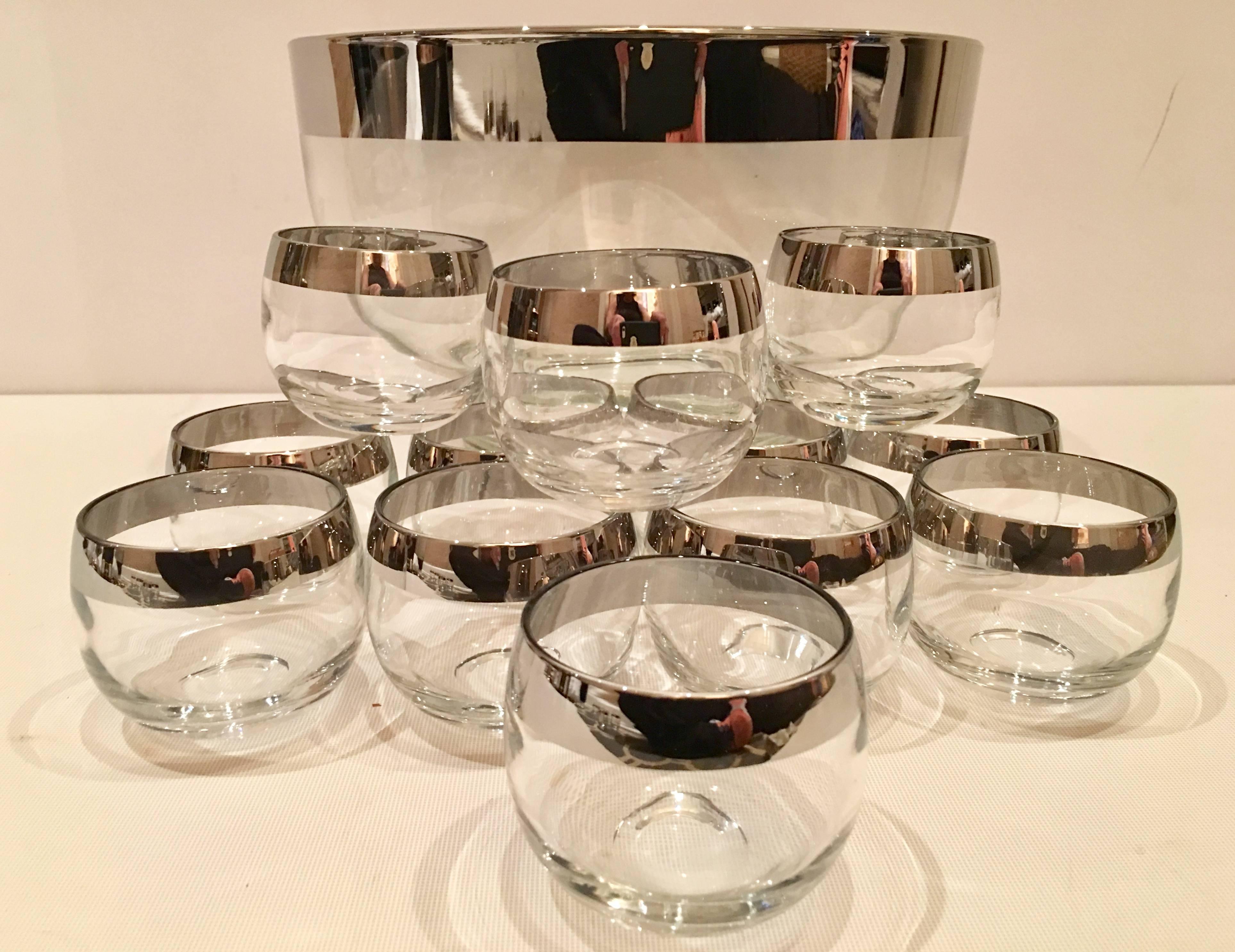 Mid-Century Modern 13 piece drinks set by, Dorothy Thorpe. Set features clear glass with a large sterling silver overlay band detail. Set includes, one large punch or serving bowl and 12 roly poly style glasses. Glasses measure, 2.5" height