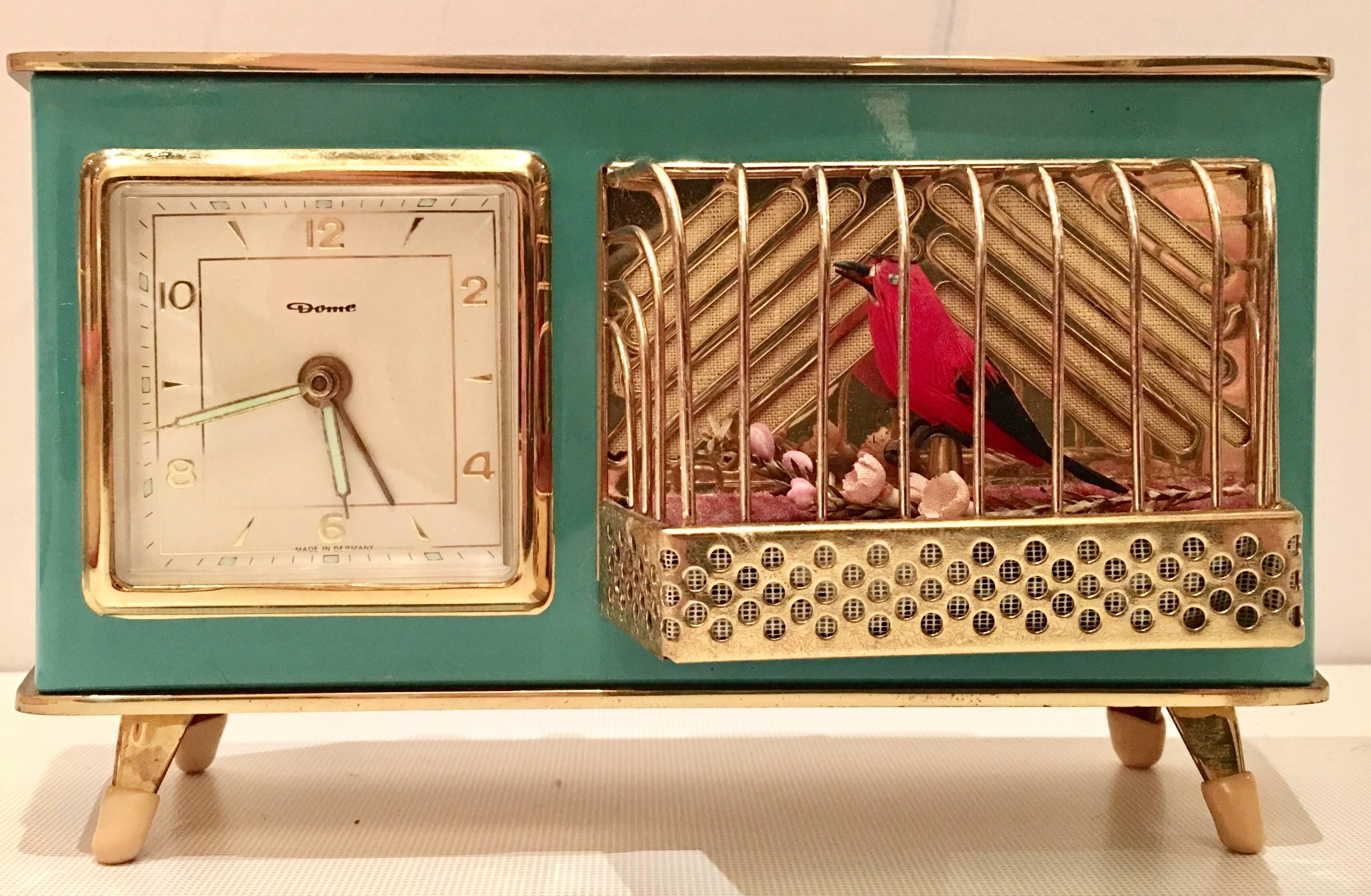 Rare 1950s brass and aqua enamel mechanical music box combination alarm clock by Dome, Germany. This fantastic singing bird in a cage tweets and osculates upon the alarm set time. The clock hands glow in the dark. The gold brass is brushed on the