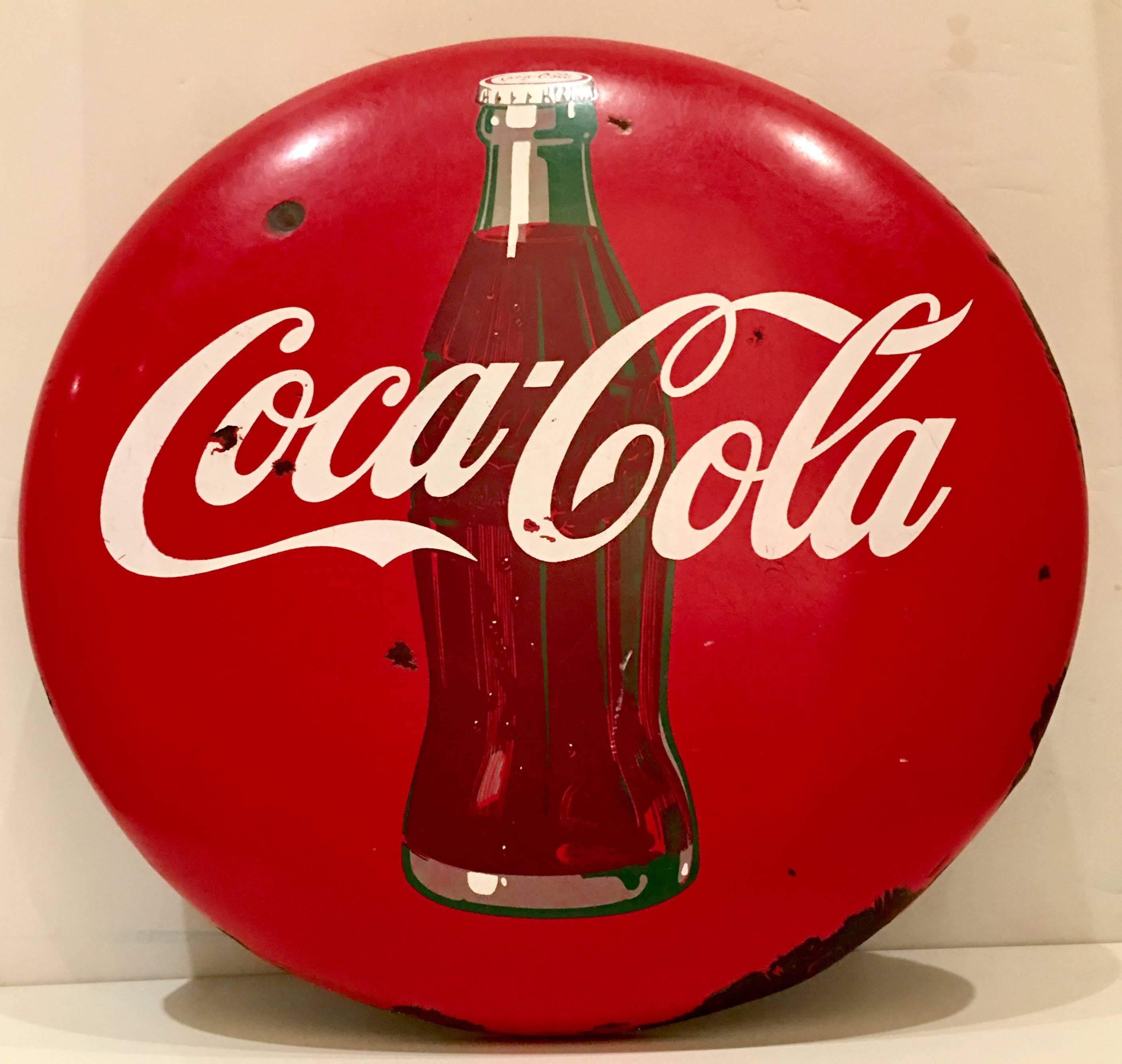 Iconic 1950s Coca-Cola porcelain advertising "button" sign. This 24" inch diameter sign depicts the iconic Coca Cola bottle.
Ready to install with existing metal wire.
