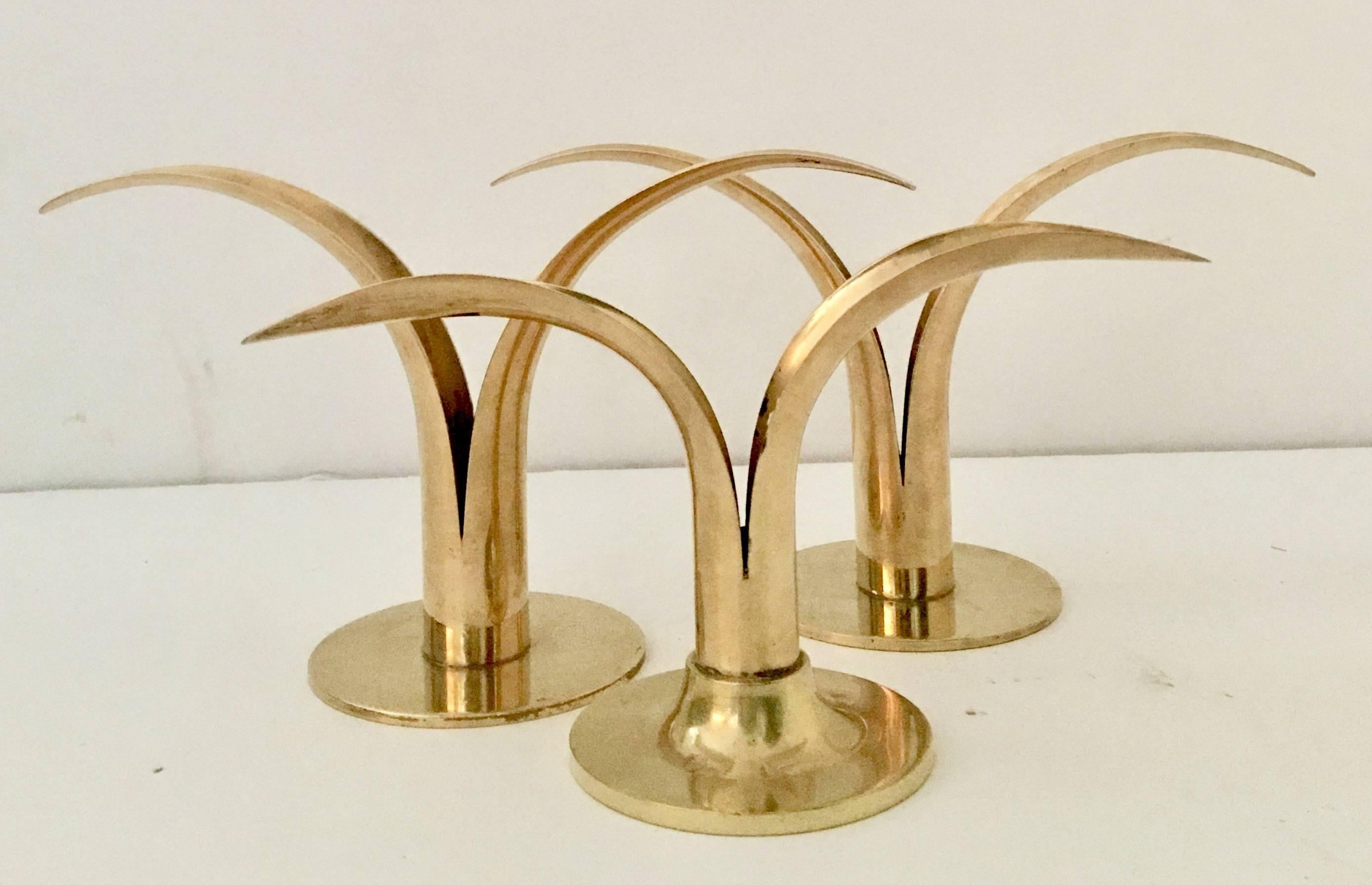Swedish set of three solid brass Mid-Century Modern "Lily" candlestick holders.
Set includes two large and one a bit smaller. The two large pieces are signed on the underside, Ystad-Metall Made In Sweden. The smaller of the three is