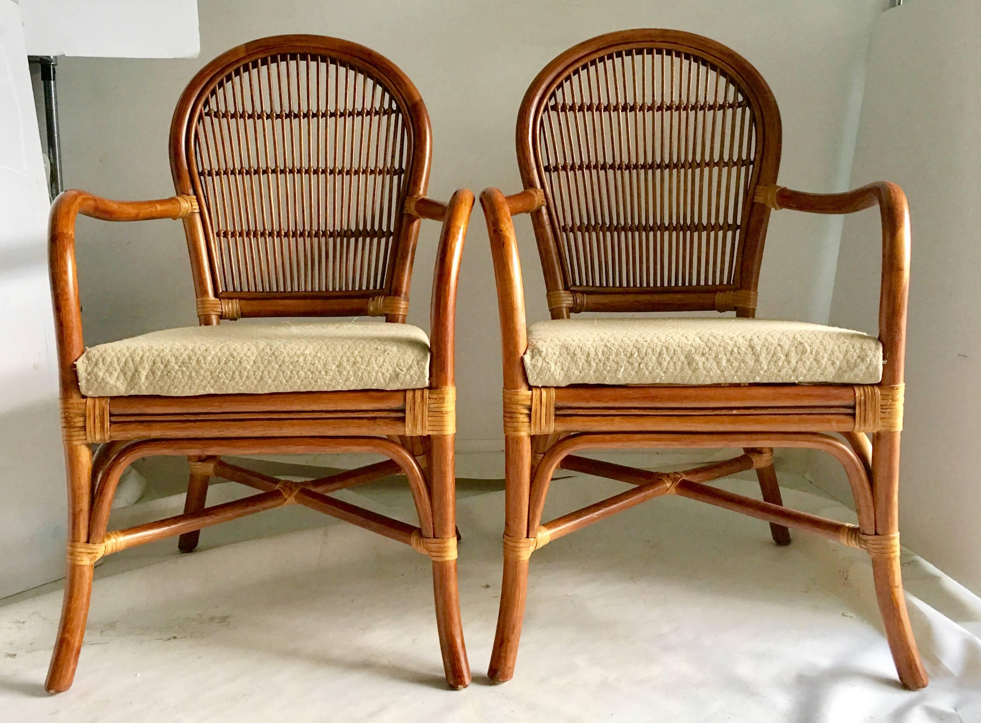 Vintage rattan bent arm rattan and wicker leather strap upholstered seat arm chairs, set of four. Features rounded open back detail with leather strap wraps. Seats are upholstered in cotton and most likely need replacing. Seat cushions are 2
