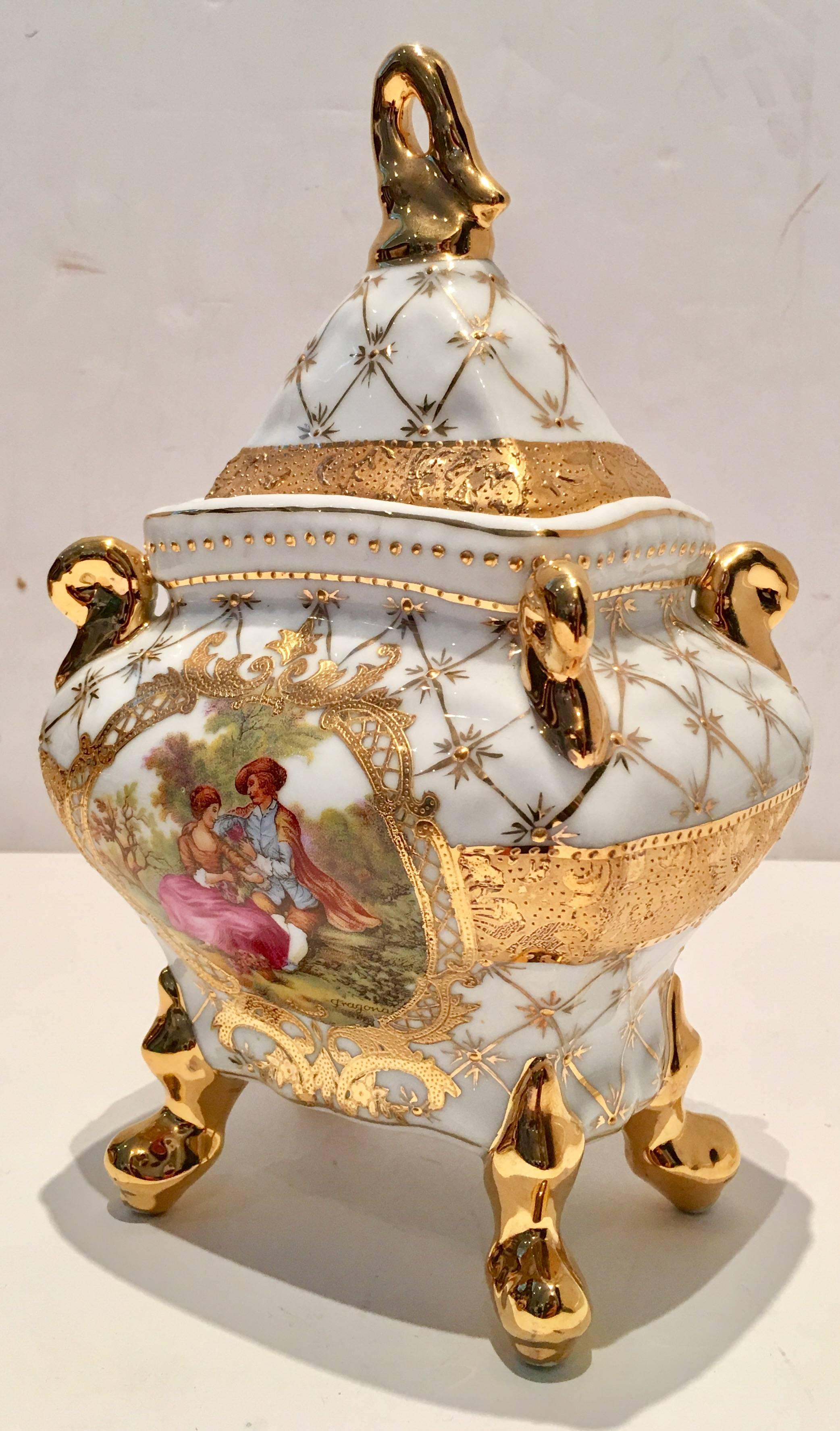 Mid-Century French Limoge style bright white porcelain footed and lidded box with 22-karat raised moriage style gold detail. Features a hand-painted bright white ground with a courting couple
motif in mostly pink, blue and green, Figural swan feet,