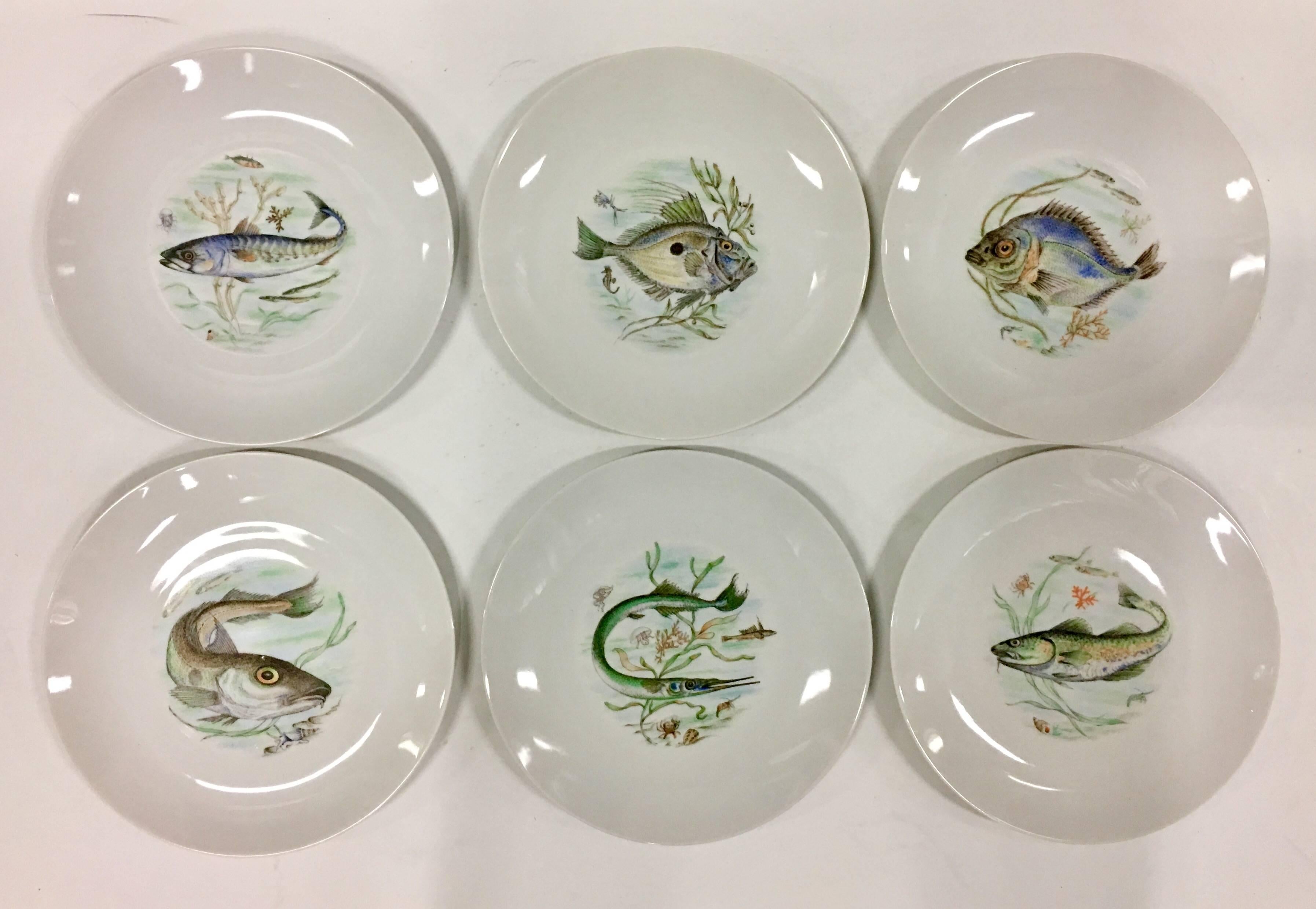 1930s German porcelain hand-painted fish service of seven pieces. Set includes six dinner plates and one large oval serving platter. Features a modern clean lined bright white ground with a pastel and earthy tone colorful sea life theme. Each piece