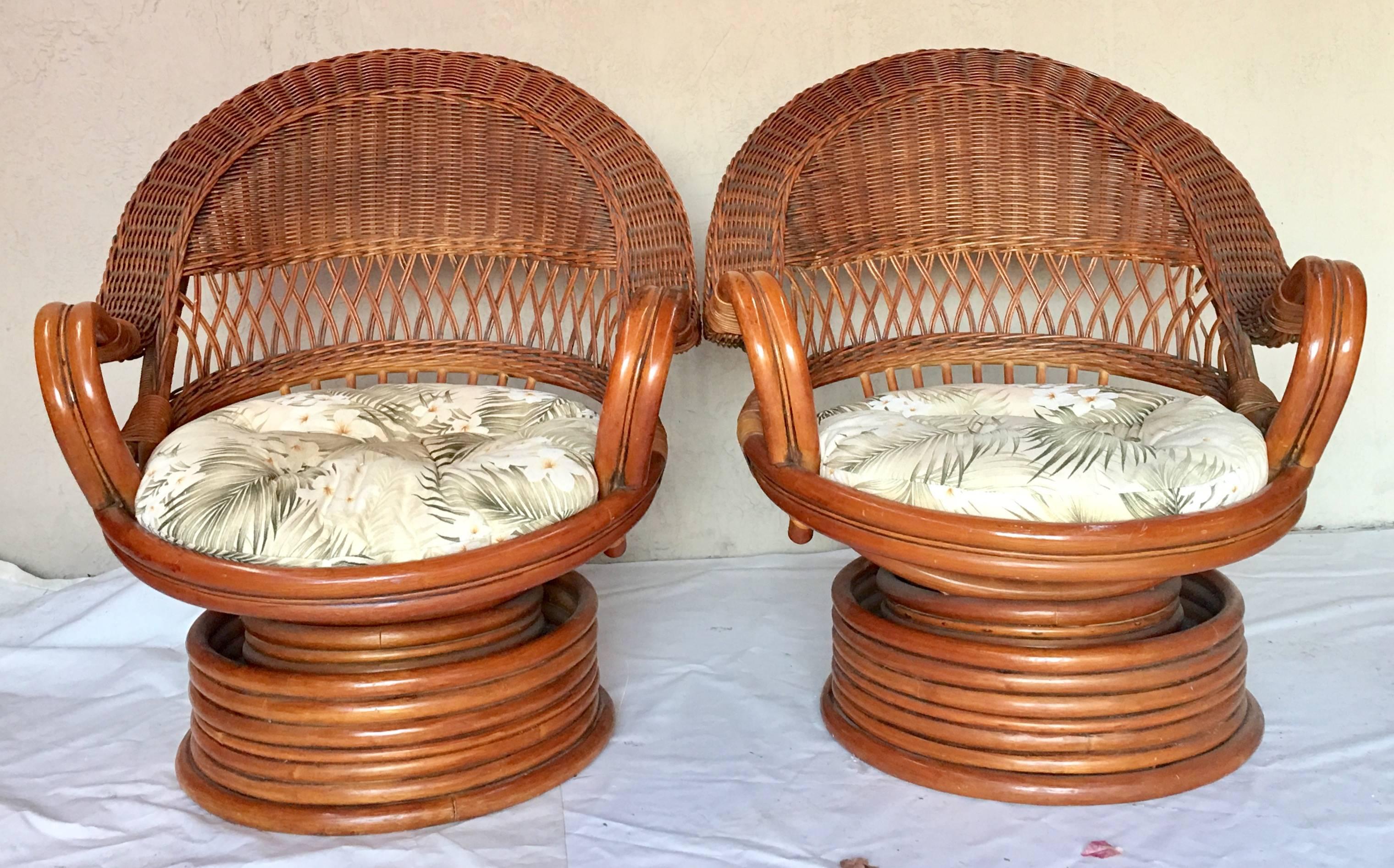 Mid-Century Paul Frankl style bent and stacked rattan and wicker high back 360 degree swivel chairs. This rare pair of rattan chairs includes vintage seat cushion with fern cotton blend indoor outdoor fabric. Cushions are button tufted on both