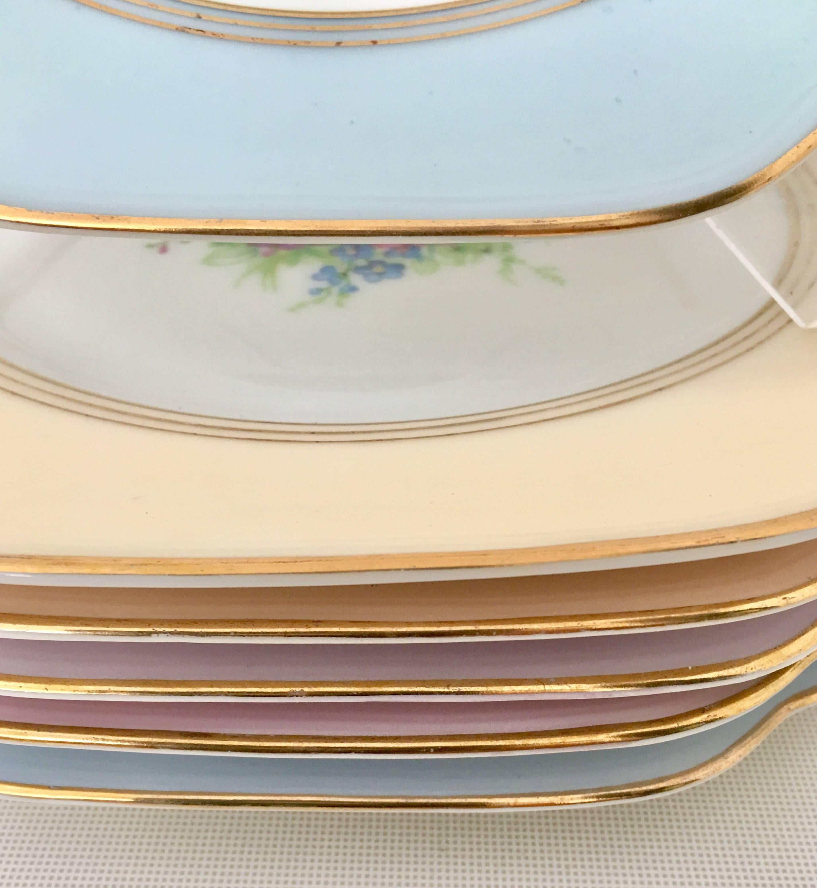 Beautiful hand-painted pastel border with central floral boquet and 22 karat gold rim scalloped dessert plate set of seven pieces by, Charles Arenfeldt, France. Each plate has a different color band and each plate is signed on the underside, France