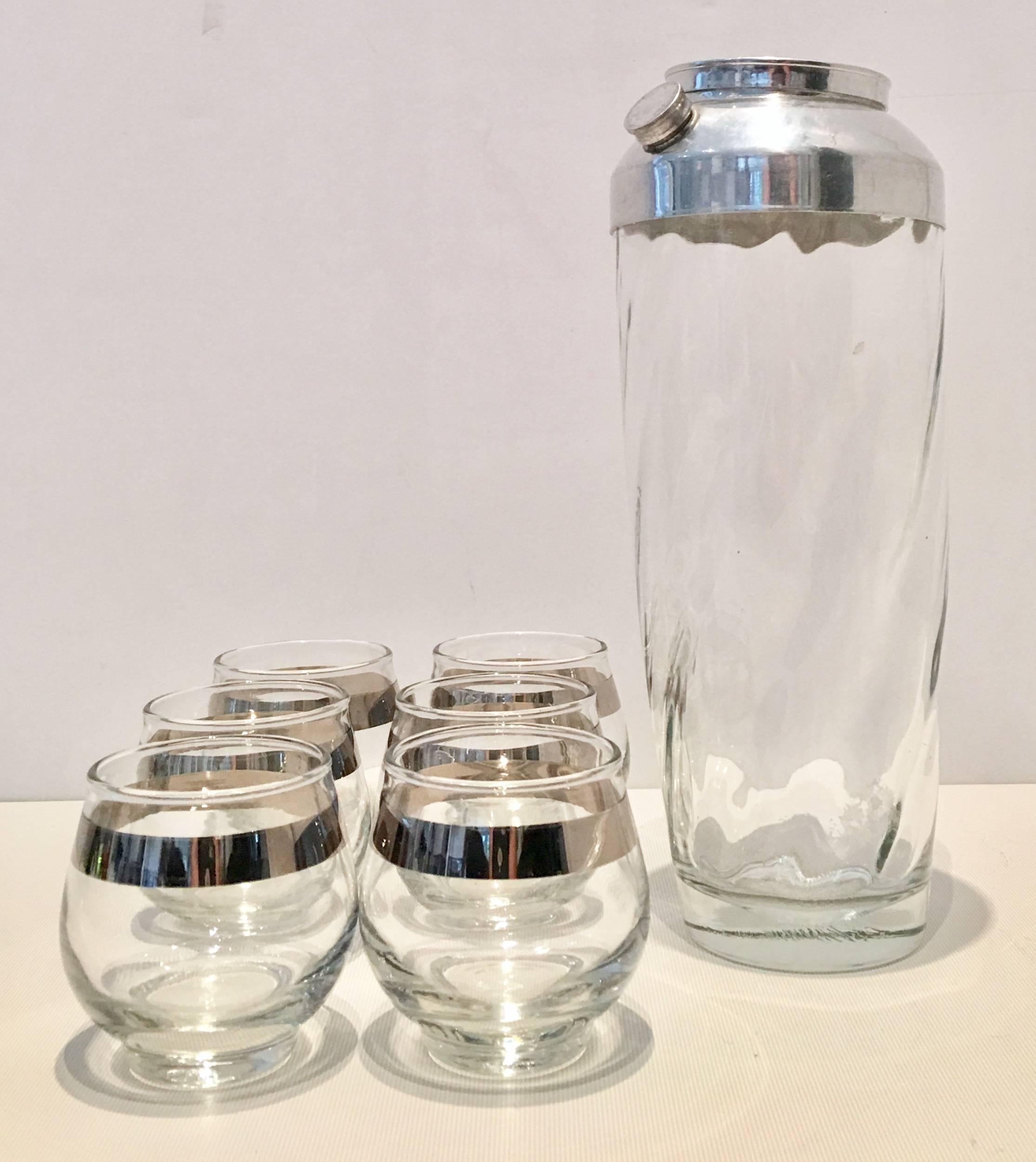 Mid-Century eight-piece drinks set by, Dorothy Thorpe. Set includes, six roly poly sterling silver overlay detail drink glasses and one three-piece cocktail Shaker, made of optic blown glass and silver plate top.
Roly Poly glasses measure,