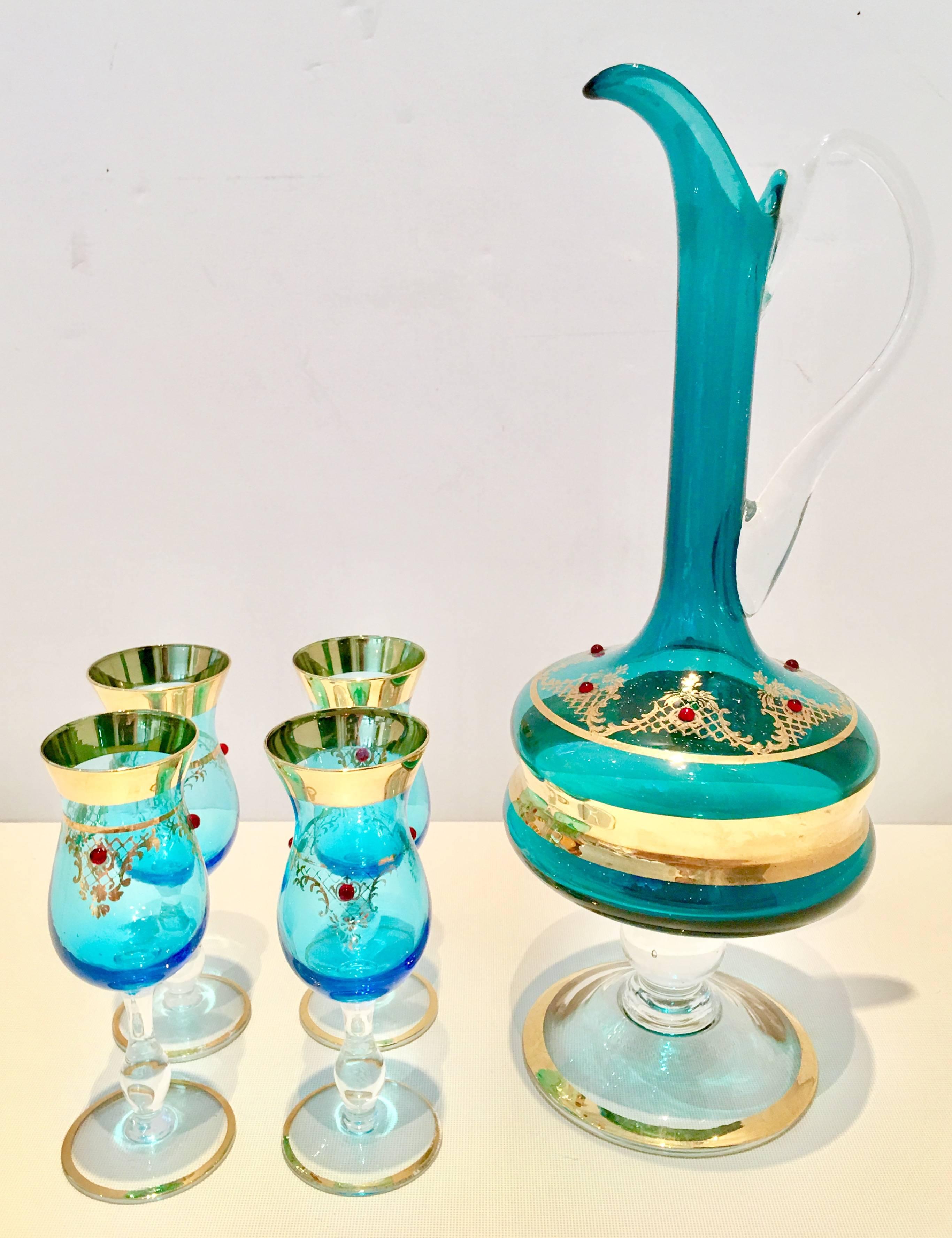 Italian Venetian glass footed and applied handled pitcher with four footed cordial stem glasses. Teal in color with generous 22-karat gold detail and apothecary style foot and modern body. The pitcher has a long spout, clear applied blown glass