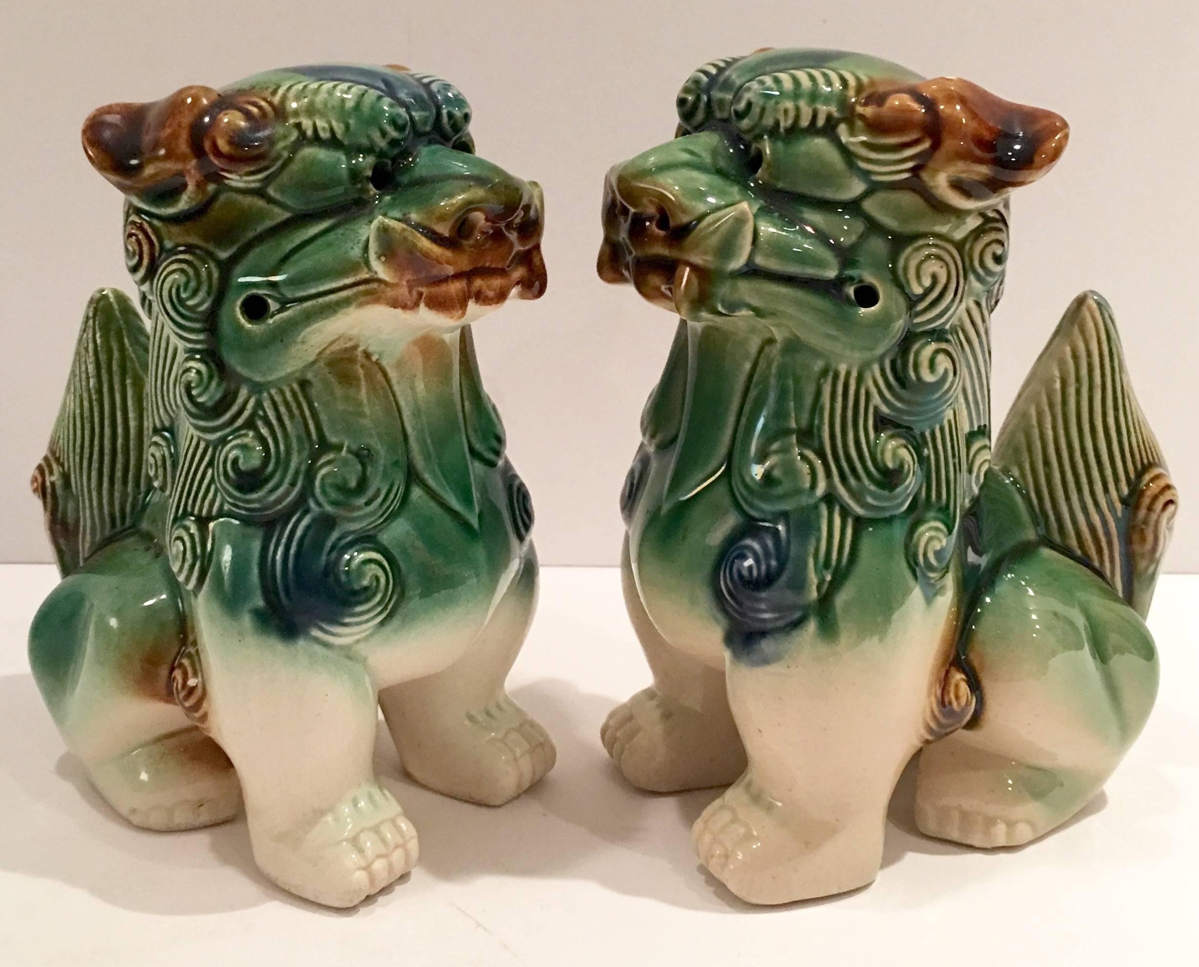 Vintage Pair Of Ceramic Glaze Polychrome Chinese foo dog sculptures. Features a color palette of cream, green blue and brown.