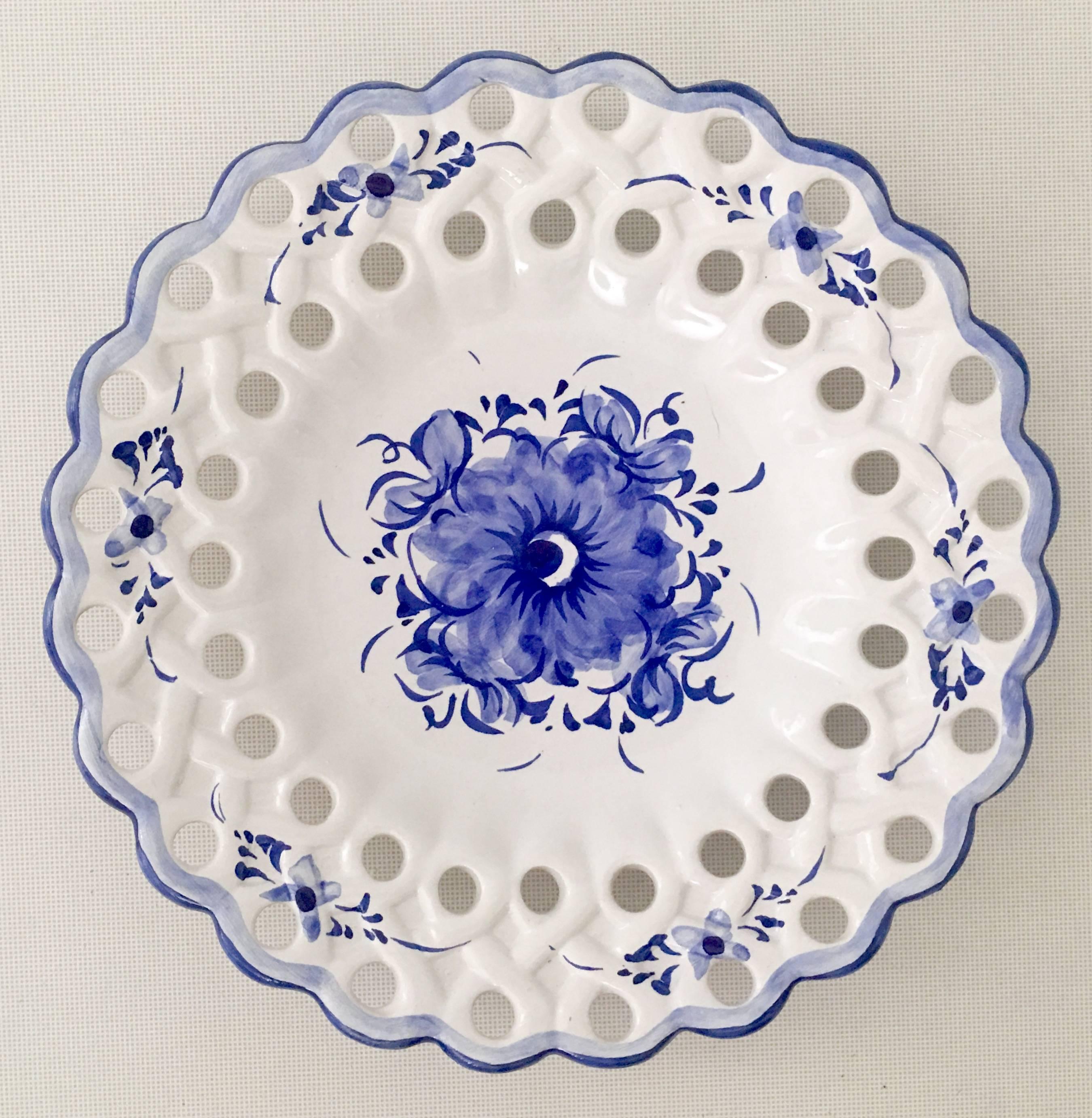 A rare set of three Vestal Alcobaca hand-painted blue and white pottery hanging wall plates. These hand-painted round plates feature a blue and white floral motif, with a reticulated and scalloped edge. Each plate had existing wire for hanging. The