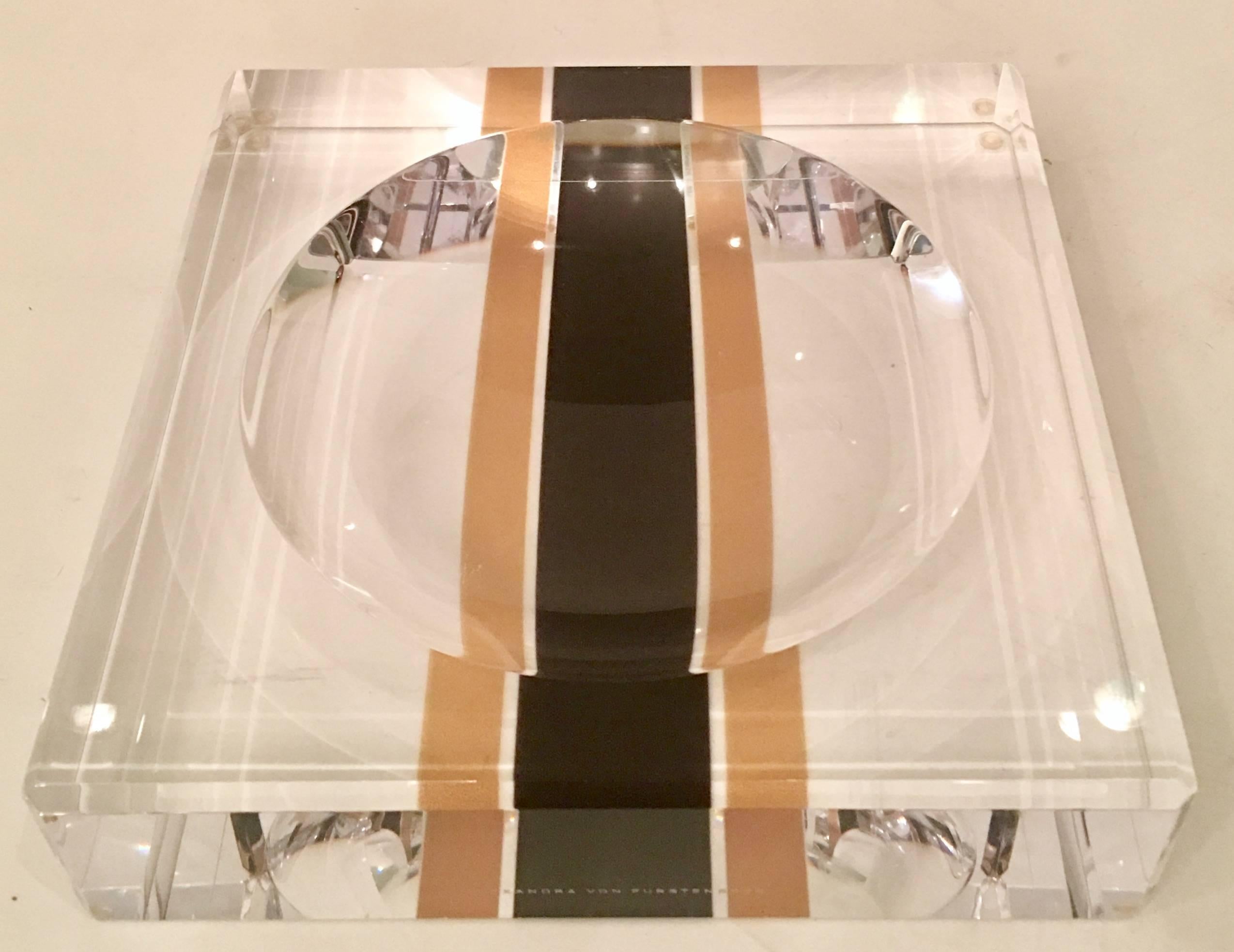 Contemporary Lucite two inch thick clear acrylic printed racing stripe square bowl by, Alexandra Von Furstenberg. Features a brown and copper central stripe with a carved cut-out central circle/bowl within a square. Hand polished to a high gloss