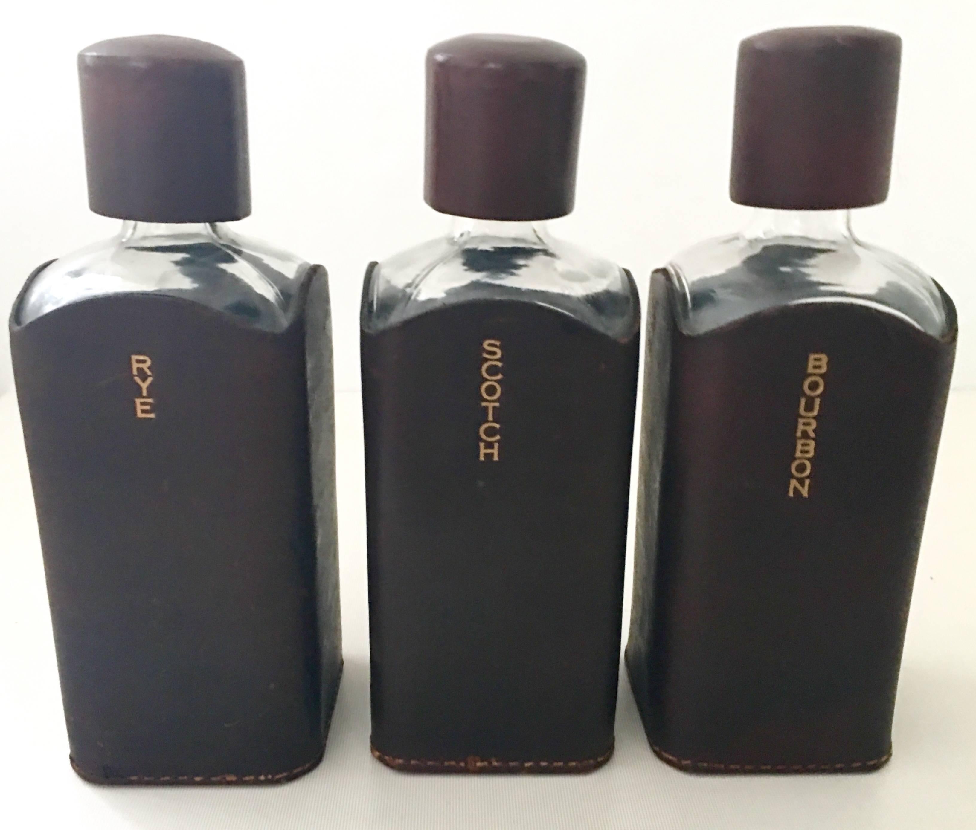 Mid-20th Century English set of three leather wrapped liquor bottles and carrying caddie by, Albro. This fantastic and complete travelling liquor bottle set features a gorgeous leather handled carrying caddie that perfectly fits three leather