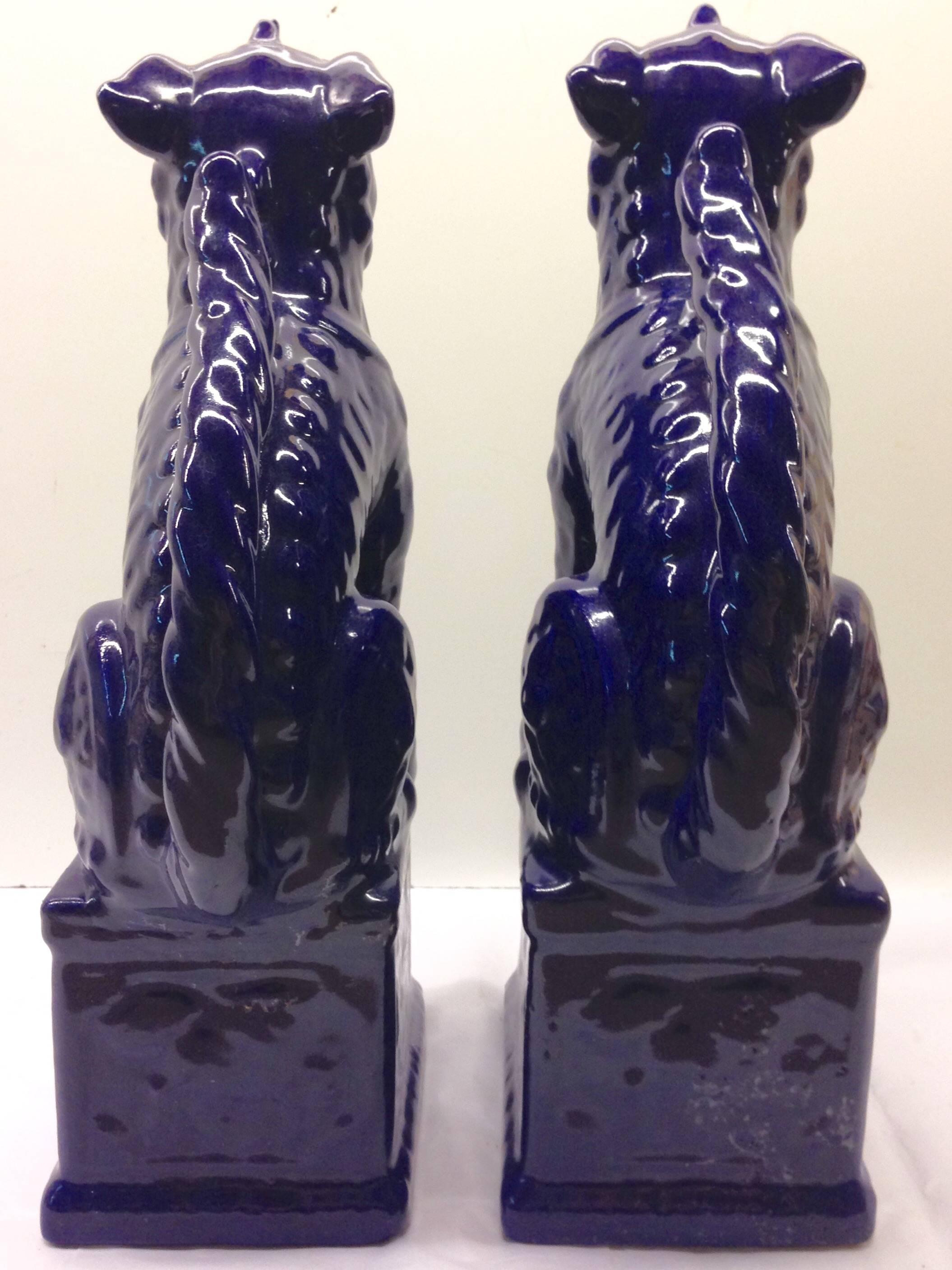 Contemporary pair of Chinese Foo Lion sculptures. These tall vibrant cobalt foo dog sculputres are made of glazed ceramic and are a high gloss finish.