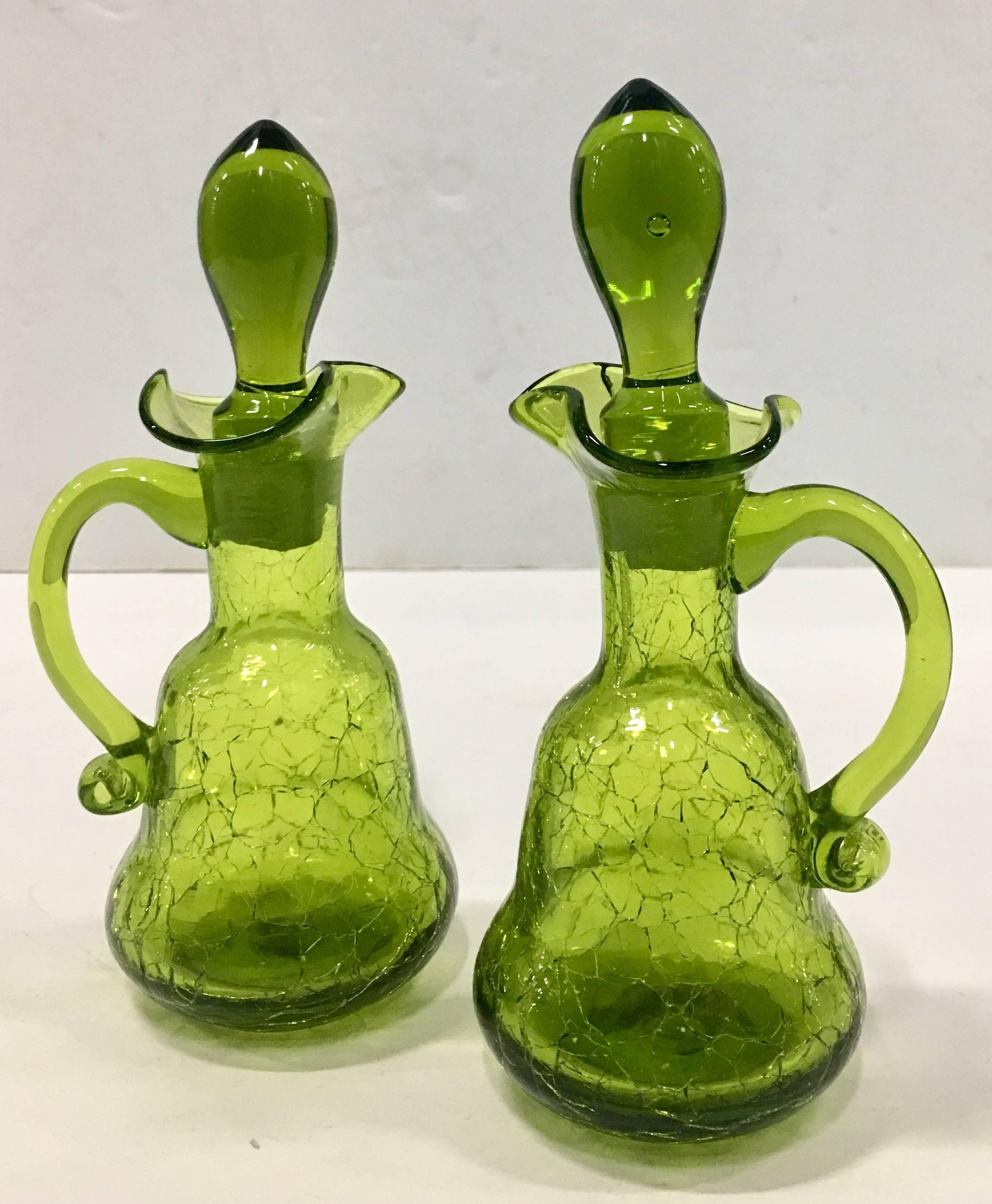 Mid-20th Century Pair of Blenko Style Blown Crackle Glass Olive Green Cruet Deanters. Features applied curved handles, ruffle neck detail and 
