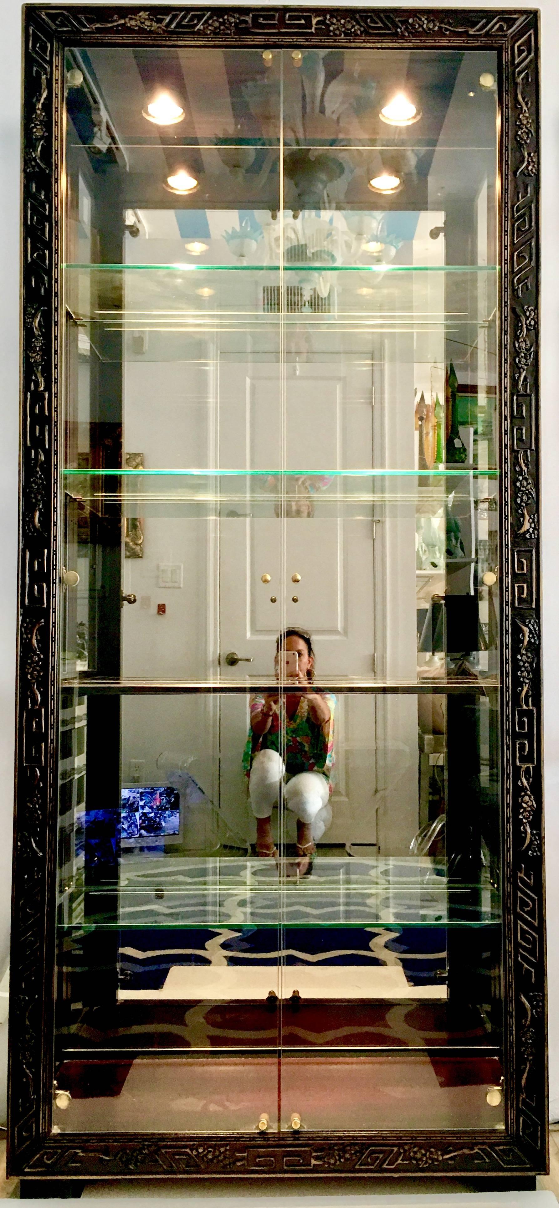 20th century lacquered black mahogany giltwood and glass framed doors mirrored shelf etegere display cabinet by, Henredon. Features mahogany wood frame with square feet, jet black lacquered with raised giltwood Greek key motif detail. Original
