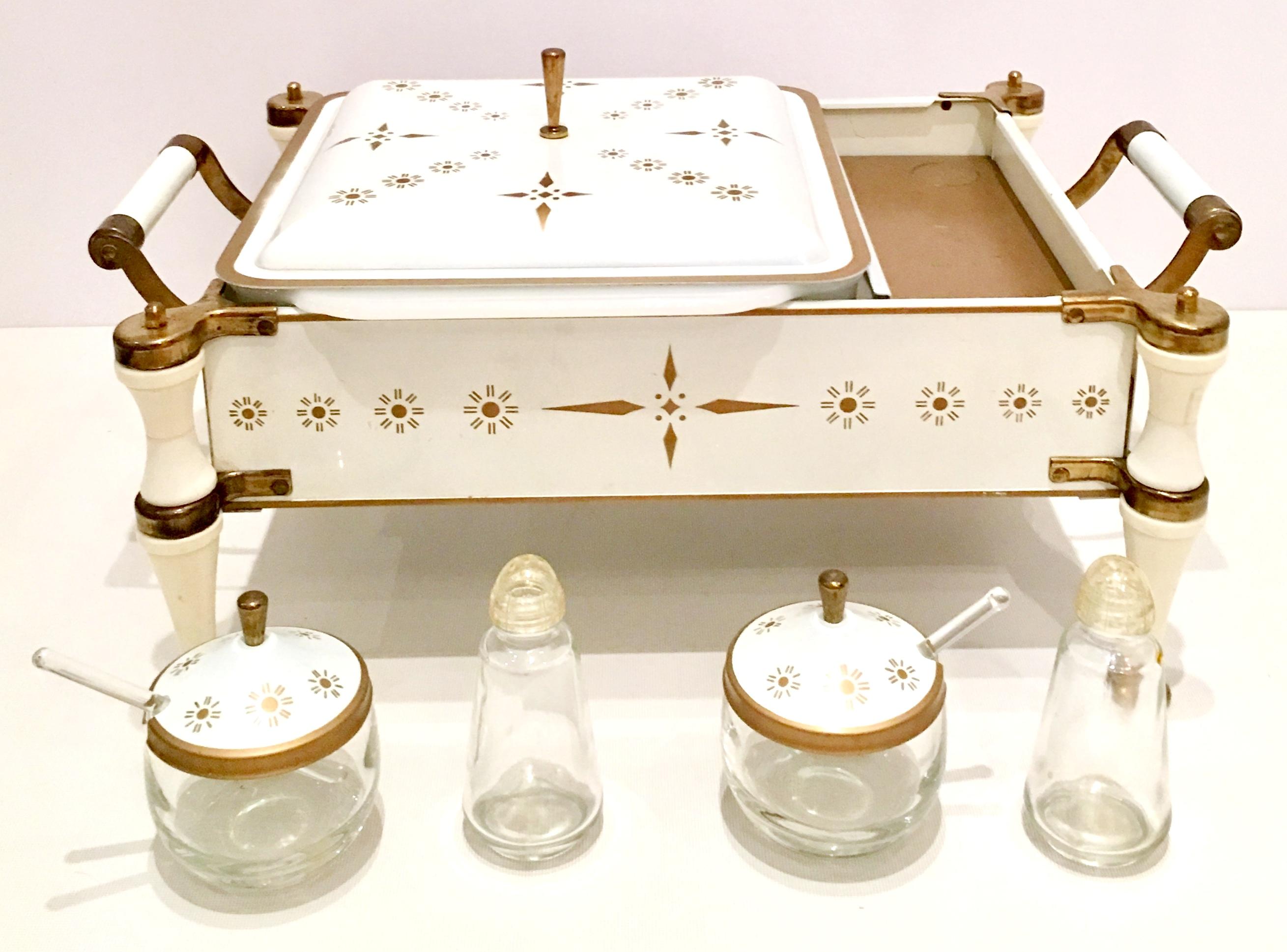 20th century enameled metal and brass chafing warming dish set of eleven pieces by, Fire King. For Anchor Hocking. Features a white and gold tone geometric enameled motif, with brass feet, handles and lid knobs.
Set includes, 1 opaque white Pyrex