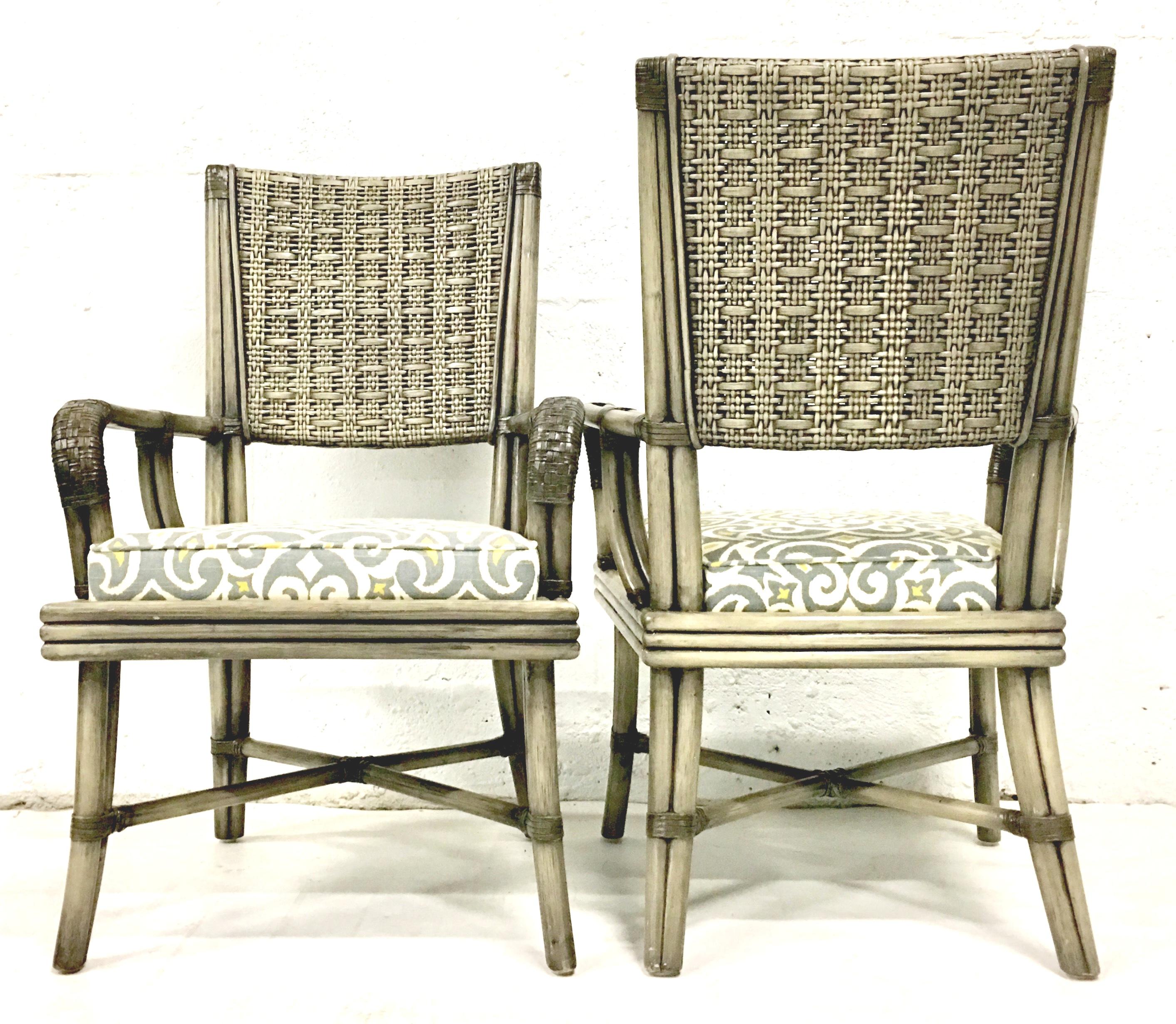 21st century contemporary pair of rattan upholstered armchairs by, David Francis. Features a stained grey wash gloss finish with leather wrap and woven detail. Upholstered in a cotton blend indoor-outdoor, white, grey and yellow self welt fabric.