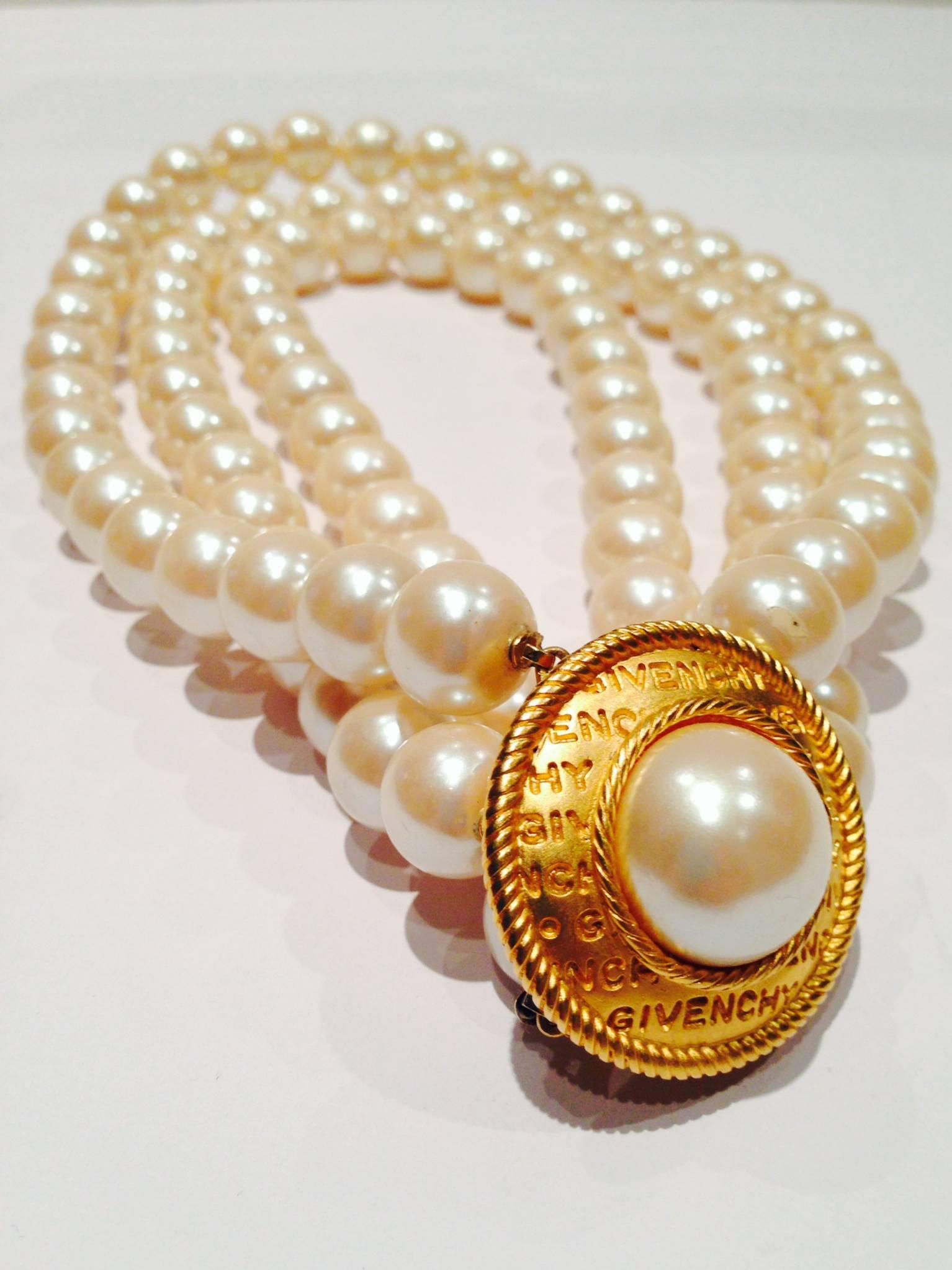 Vintage Givenchy signed gold tone logo clasp three-strand faux pearl bead choker style necklace. Clasp measures 1.75" inches diameter and can be placed anywhere on the neck. Each pearl is approximately 1.5" diameter. A substantial neutral