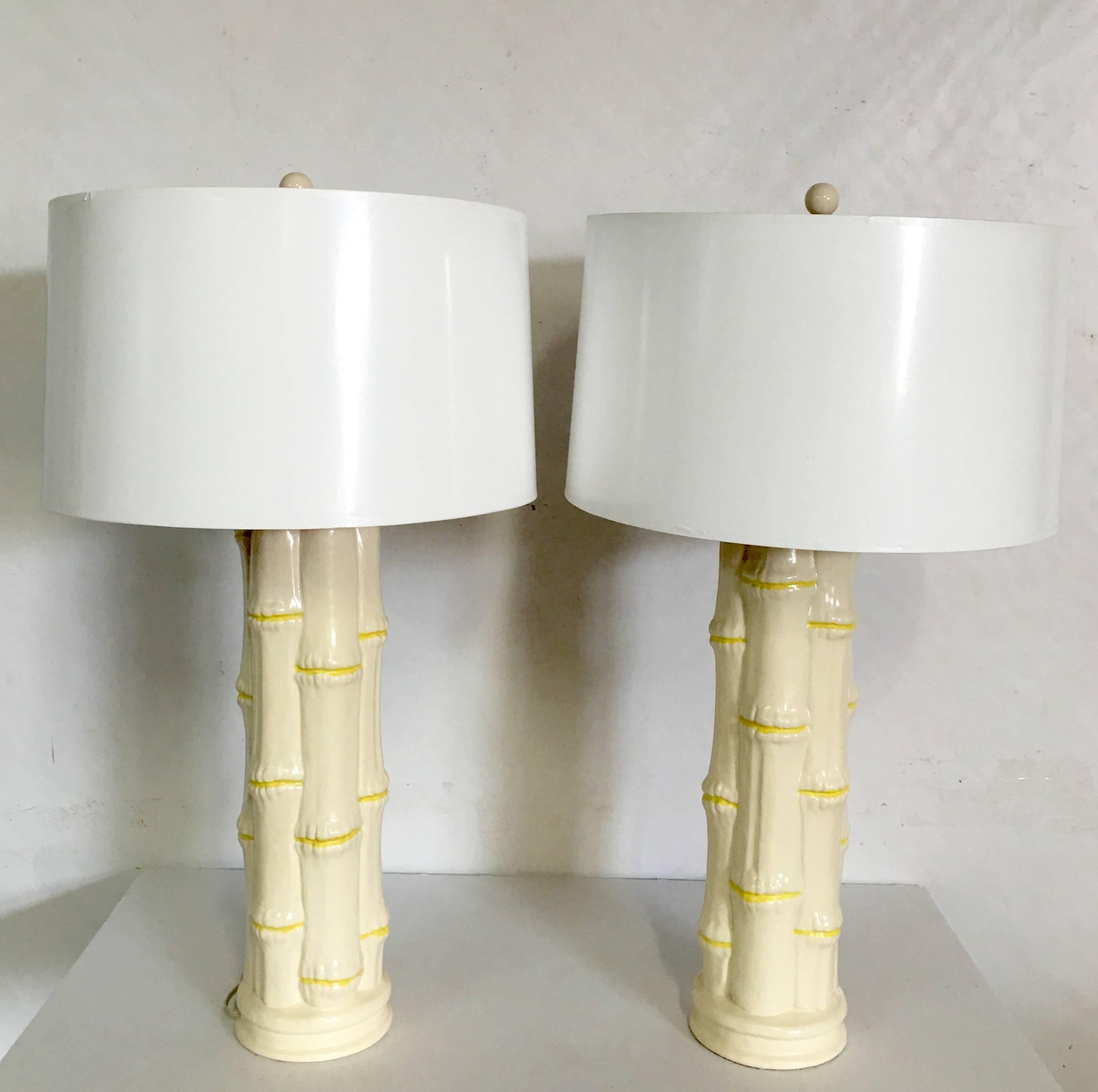 Mid-Century Pair Of Tall ceramic white and yellow faux bamboo hand painted lamps. Original brass finials, pristine condition. Wired for the US and in working order. Takes a standard light bulb, max watts 250. Height to socket measures: 25.5