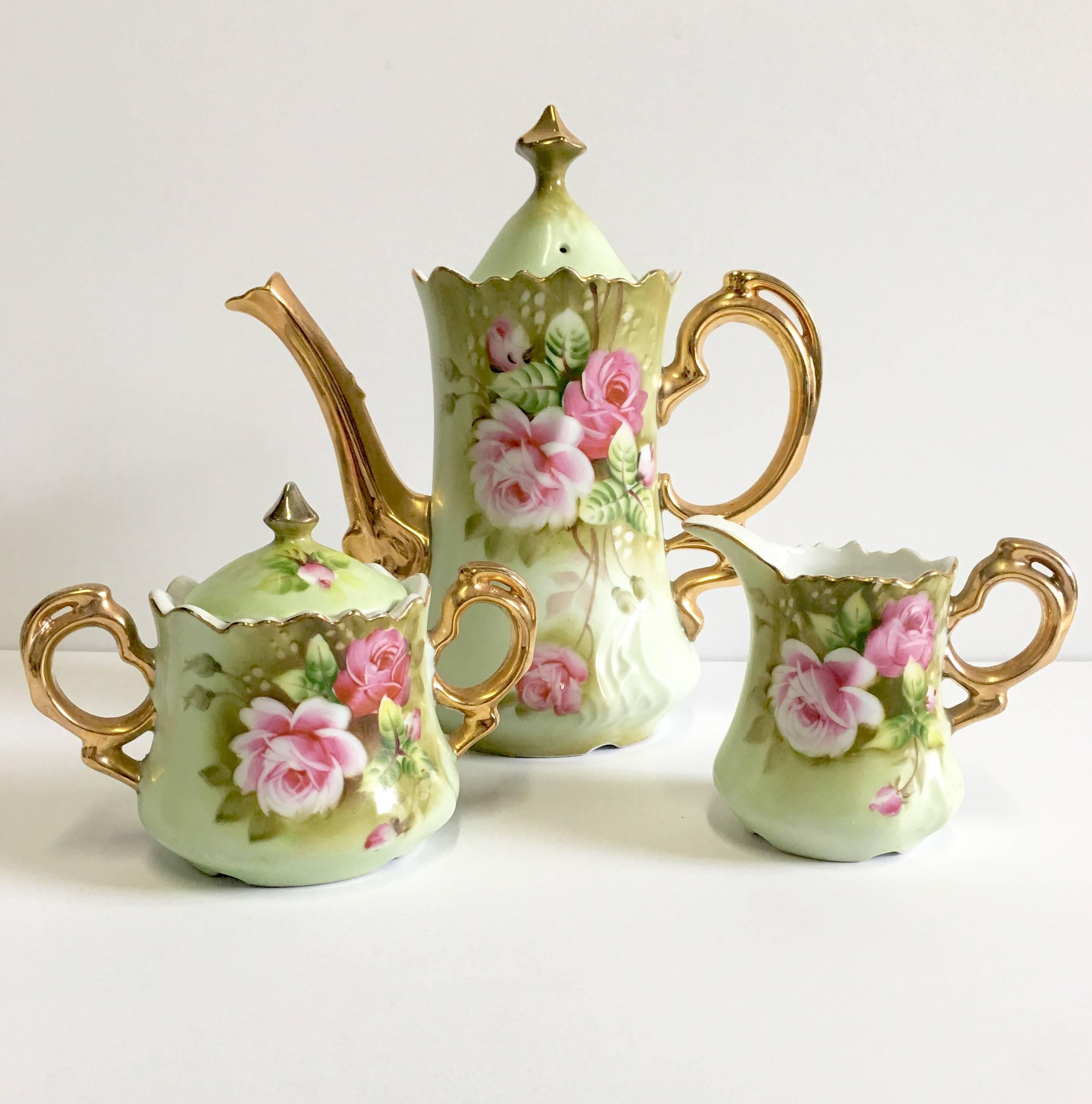Beautiful mint green, pink and 22-karat gold adorned tea/ coffee service. Set includes, lidded tea/coffee pot, lidded sugar bowl, handled creamers and six tea/coffee cups and saucers. Hand-painted, each piece is signed on the underside, Lefton