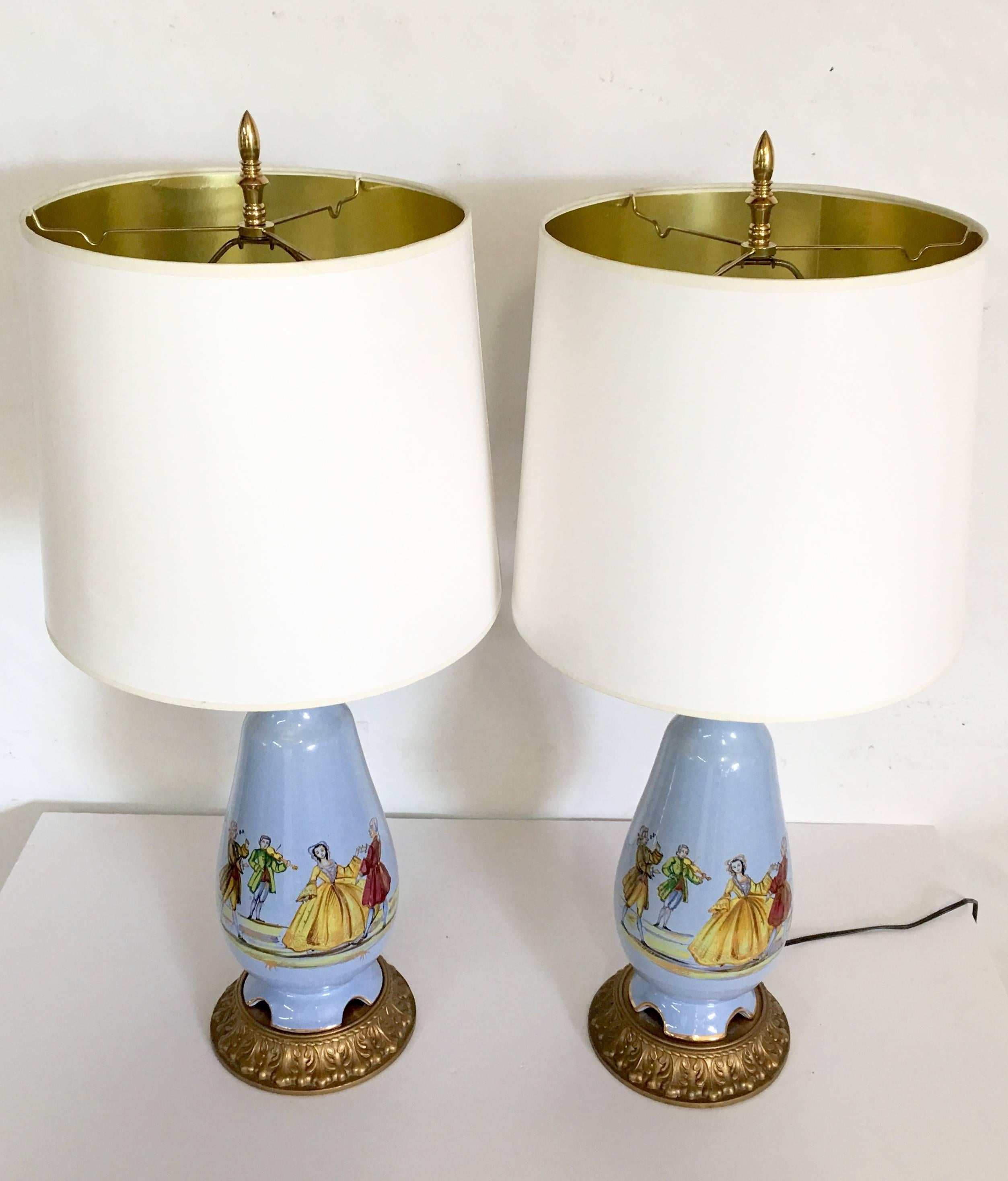 Mid-Century Pair Of Whimsical & Unique French Blue Porcelain Decalcomania Table Lamps. Features a 17th Century courting couple dancing to French court musicians.
Mounted on original gold gilt bronze bases with gold bronze ribbed necks. Includes