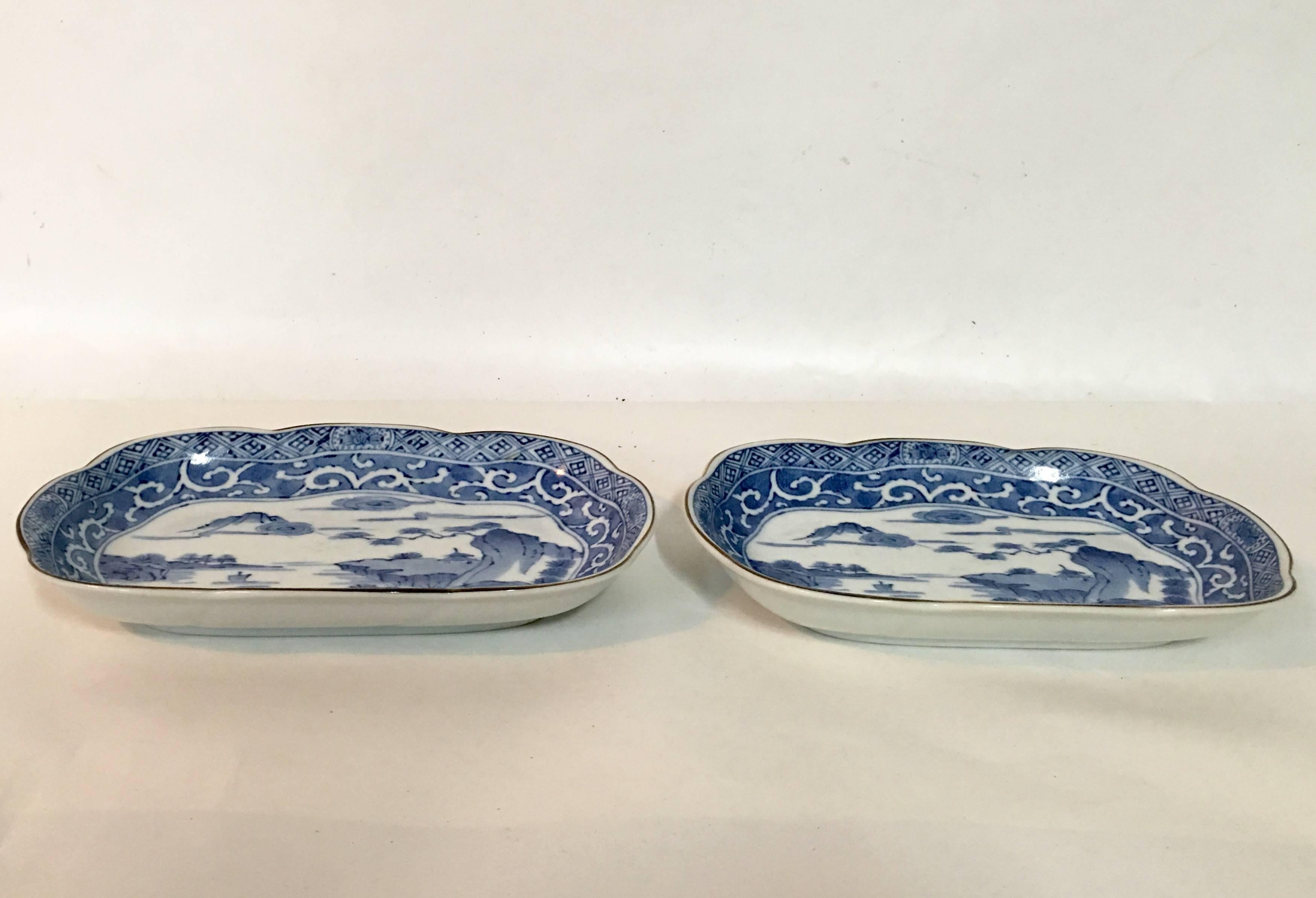 Pair of blue and white Japanese hand-painted gold rim scenic motif platters/trays. Each piece is artist signed on the underside.