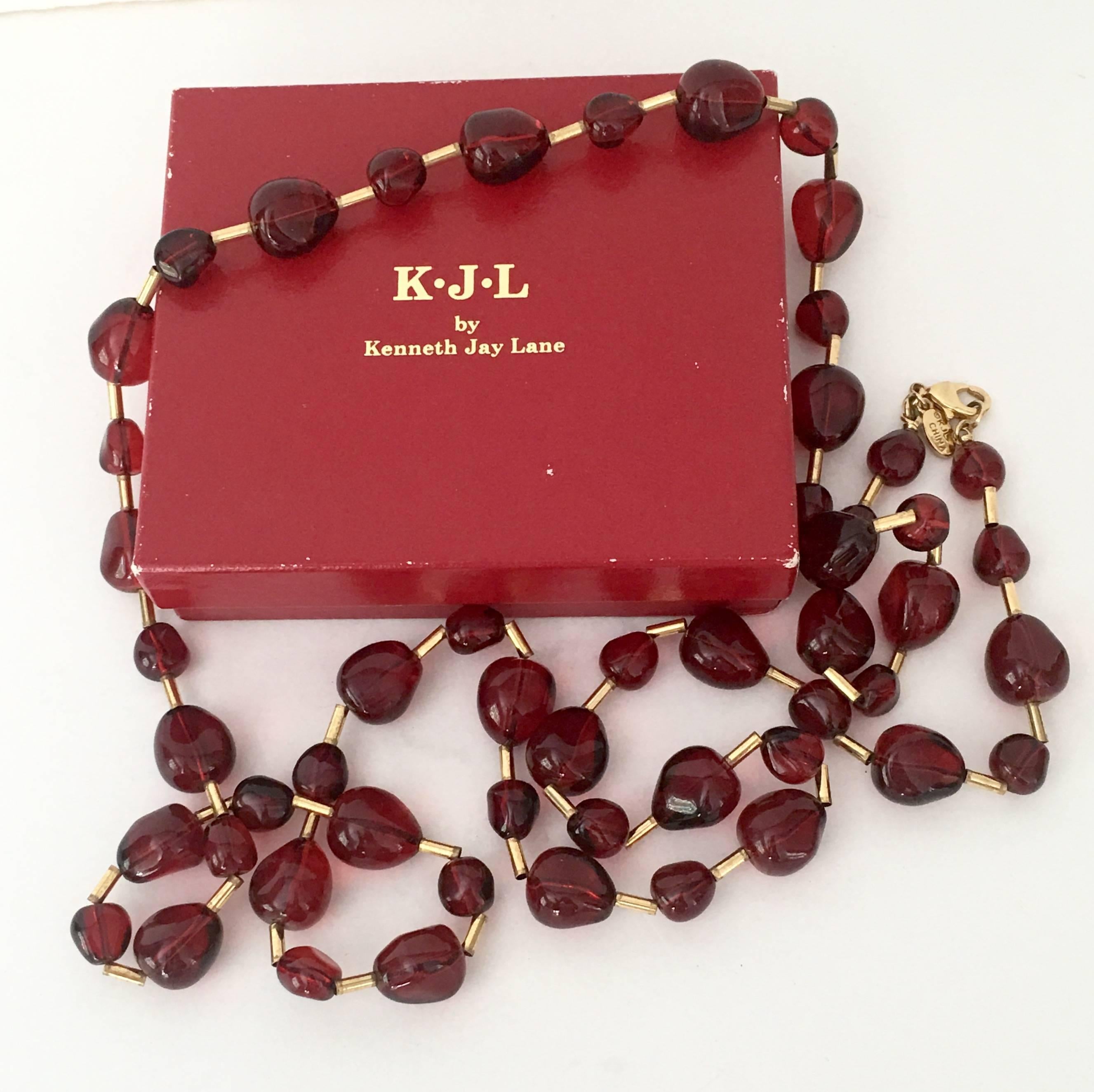 Kenneth Jay Lane Lucite ruby red organic shaped beads and gold plate tubular bead link opera length necklace. Each ruby red bead is 25