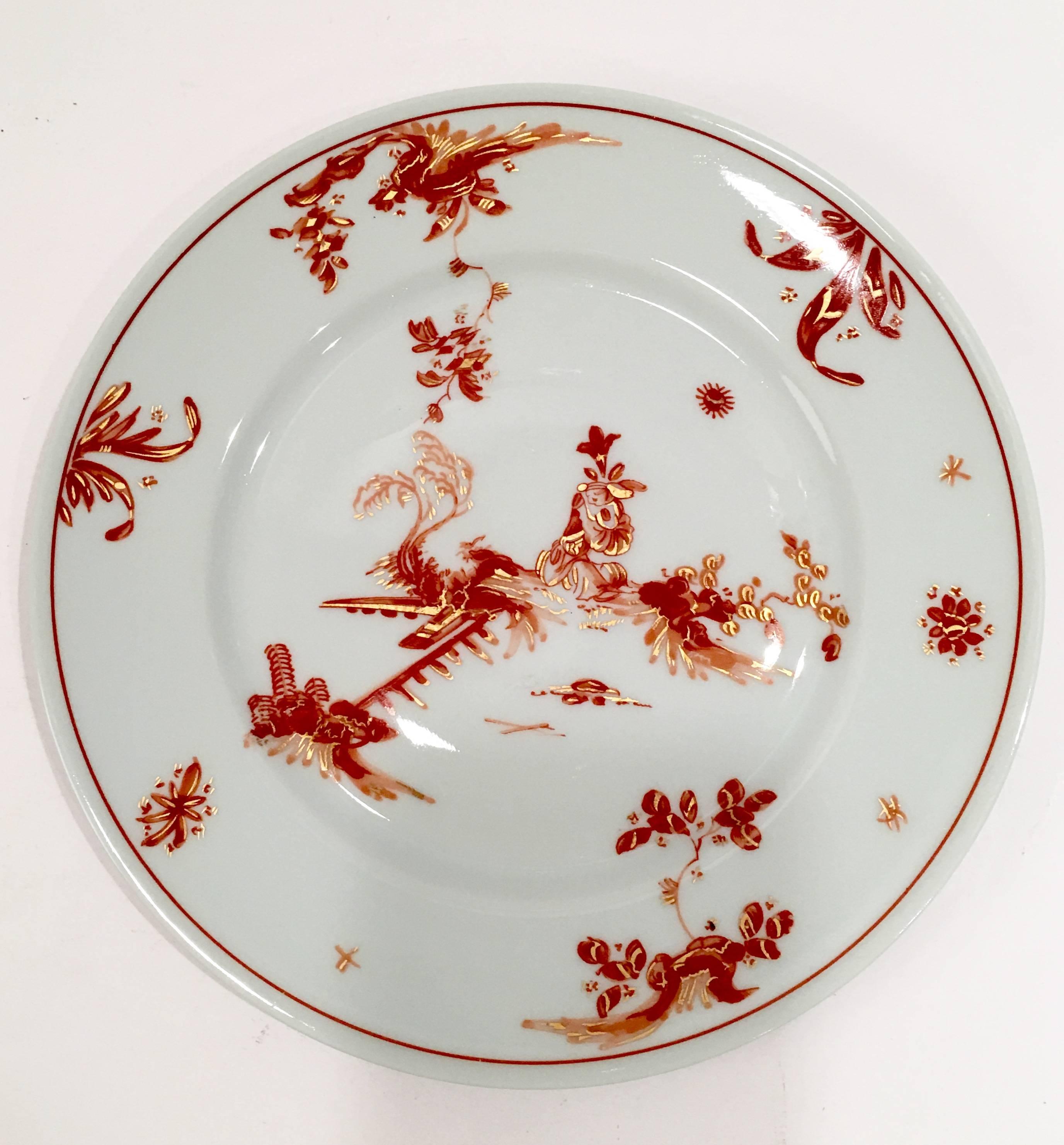 Elegant chinoiserie style porcelain plates in rust. Red and gold on top of a white ground in a floral and fauna pattern with 22-karat gold embossed detail. Each plate is signed on the underside.