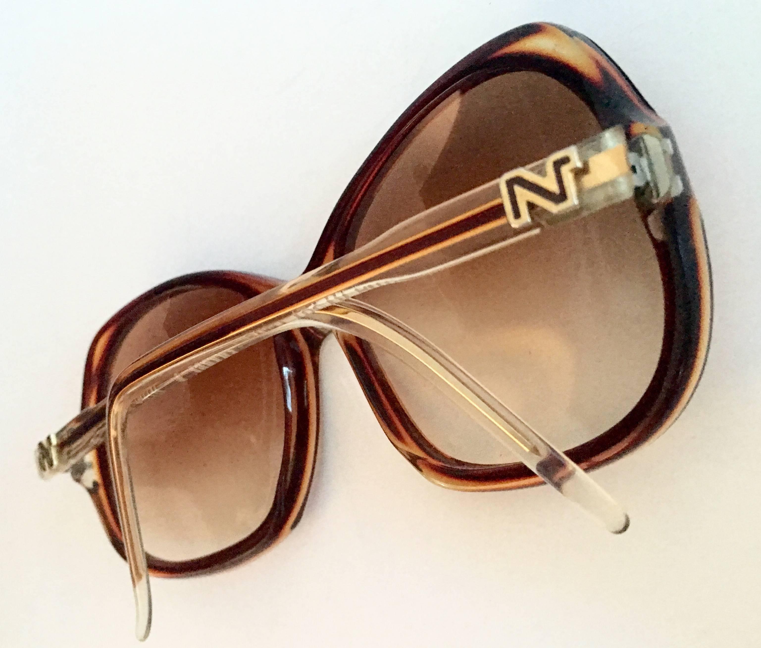 1970s Mod amber and gold designer Nina Ricci sunglasses. Ombre color and "N" logo detail. Includes original soft Nina Ricci Logo embossed protective case included.