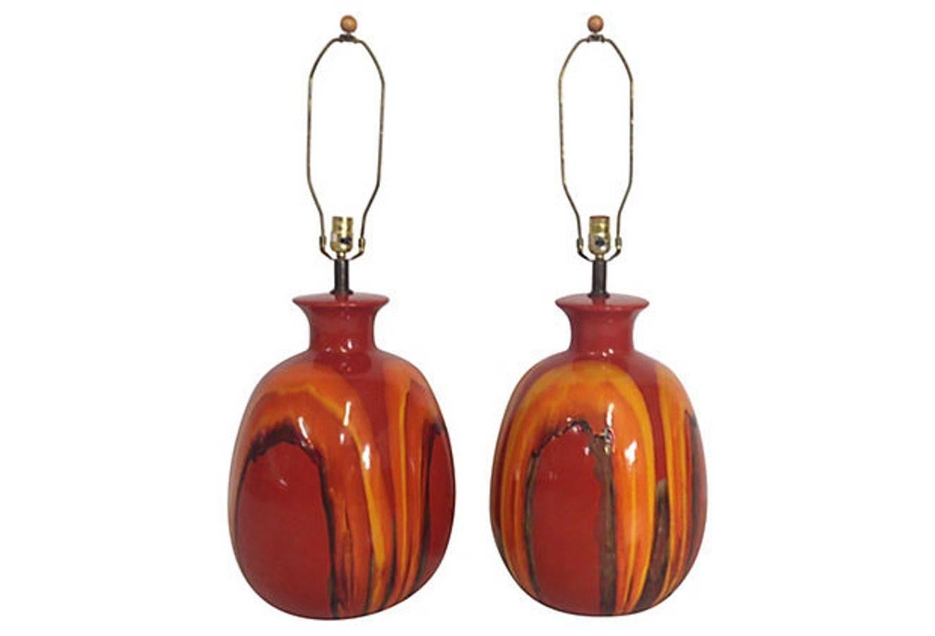 Pair of Mid-Century Modern oversize orange drip-glaze ceramic lamps. Each lamp comes with the original round walnut finial. Wired for U.S. In working order, using standard bulbs. Measures: To socket 24