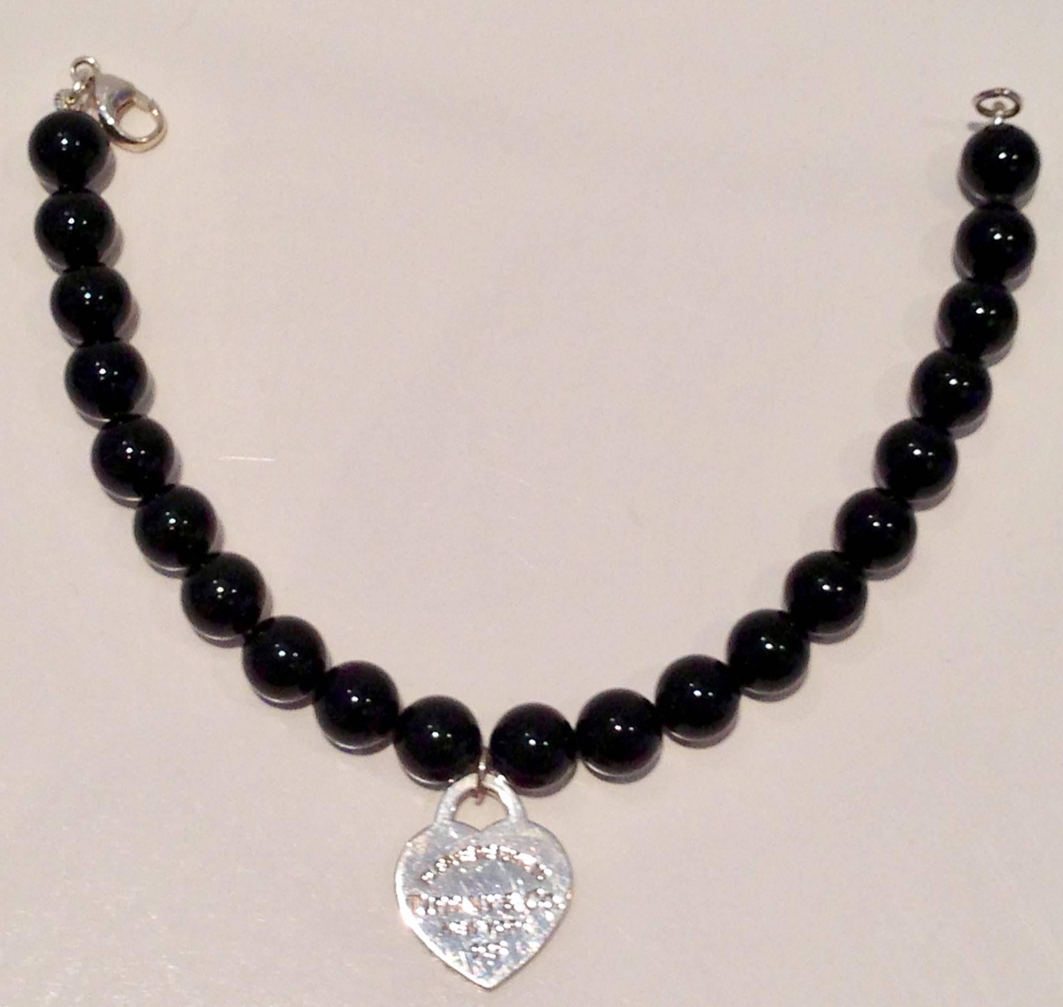 Tiffany & Co. black onyx bead and silver heart charm bracelet. Hear charm reads, please return to Tiffany & Co. Tiffany & Co. New York 925. The alternate side reads, Tiffany & Co. with space for personal inscription blank. Clasp is