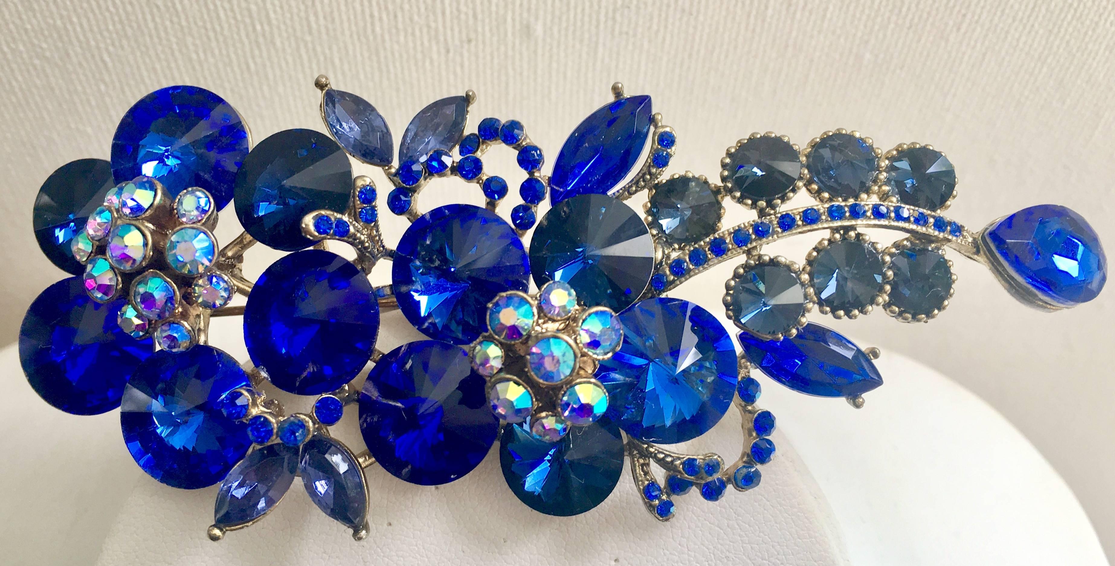 Rare, incredible and monumental peacock blue sapphire Swarofski crystal round rivoli stone double flower brooch. Set in gold tone metal featuring projected florets with Aurora borealis crystal stones. Brooch projects, 1" inch and is 4.25"