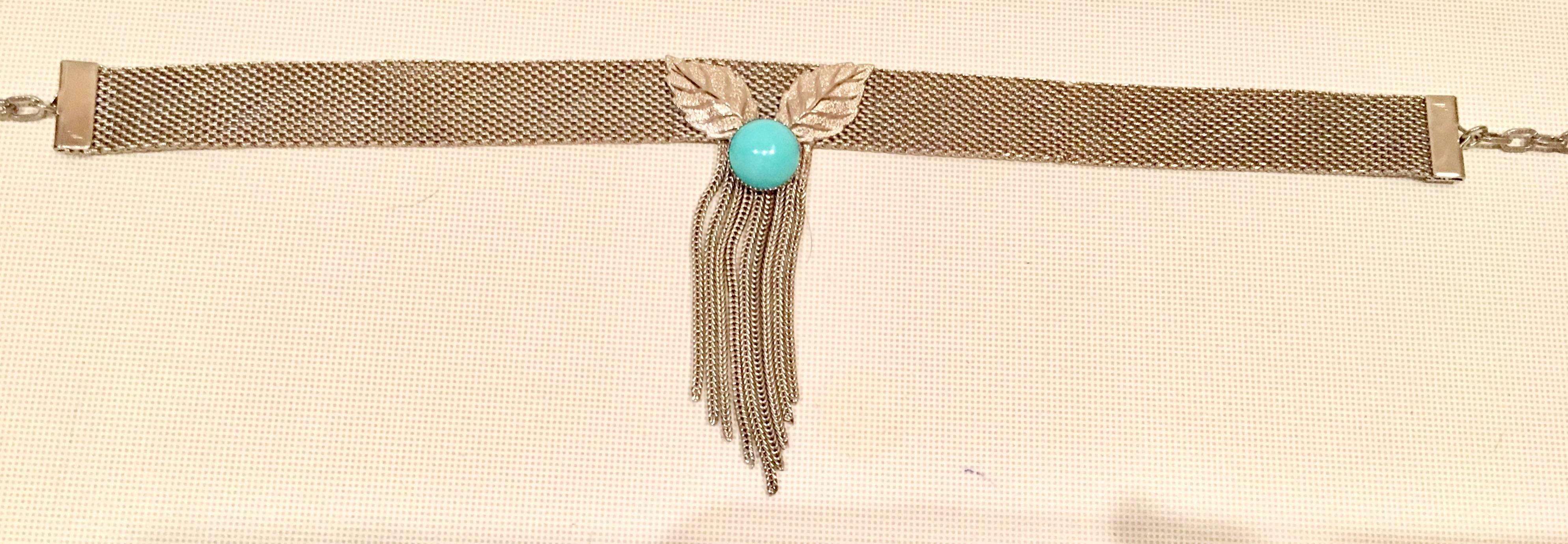 Rare silver mesh metal and faux turquoise center stone with raised and texture leaf detail choker necklace. Hook and chain closure, signed "Hobe" . Central ornament with fringe measures 3.5" inches in height. Necklace can be adjusted