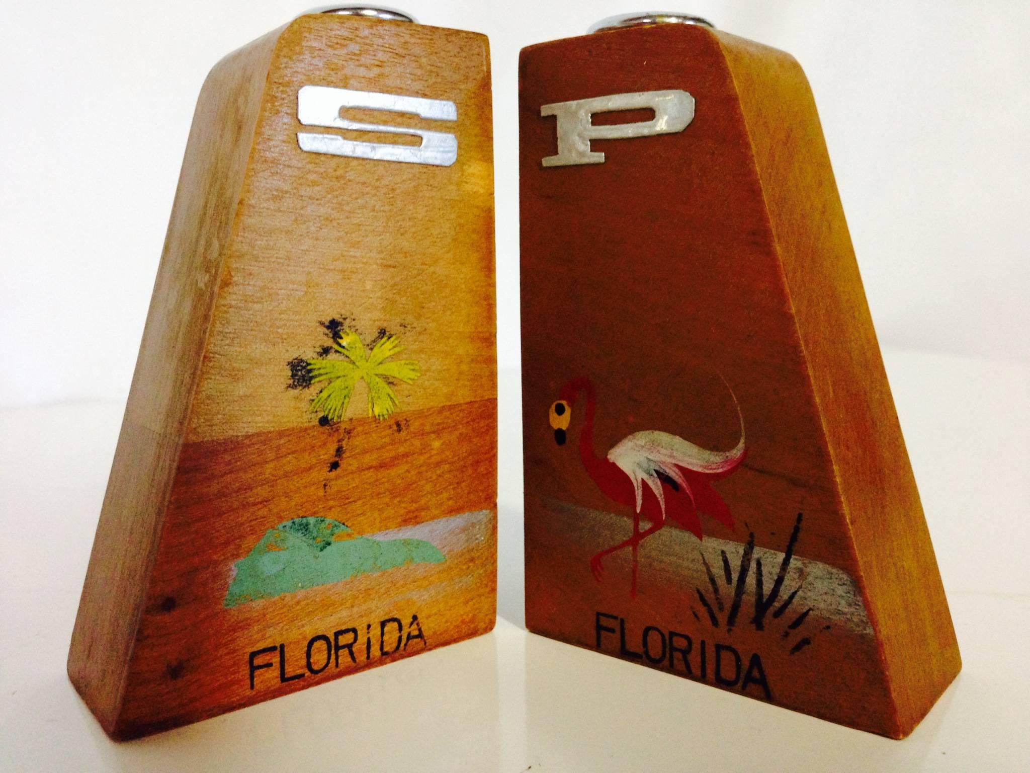 Adorable Mid-Century hand-painted teak with silver chrome S&P tops salt and pepper shakers. Features a Florida theme of a flamingo and palm tree.

