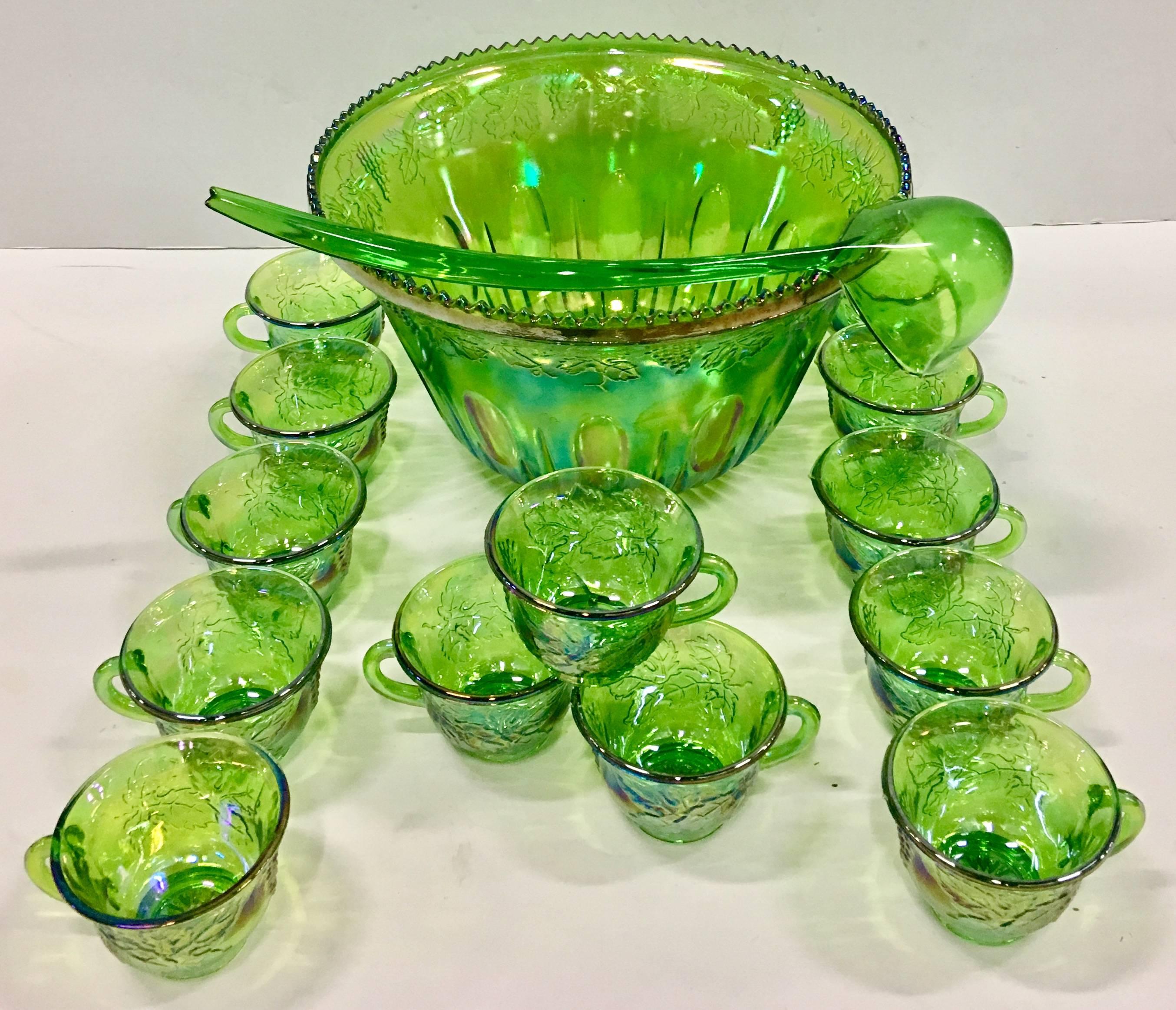 Mid-Century American Indiana glass cut seventeen piece punch bowl and cups set. Features a cut and raised grape vine pattern in iridescent lime green. Set includes, thirteen cups, one large punch bowl, one Lucite ladle and two Lucite cup