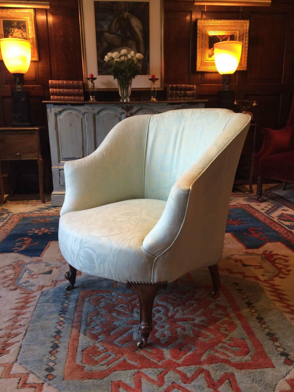 Upholstered early 20th century Edwardian Tub armchair, finished in an elegant patterned green silk fabric and raised on cabriole legs terminating with brass casters, the chair is offered in excellent condition.