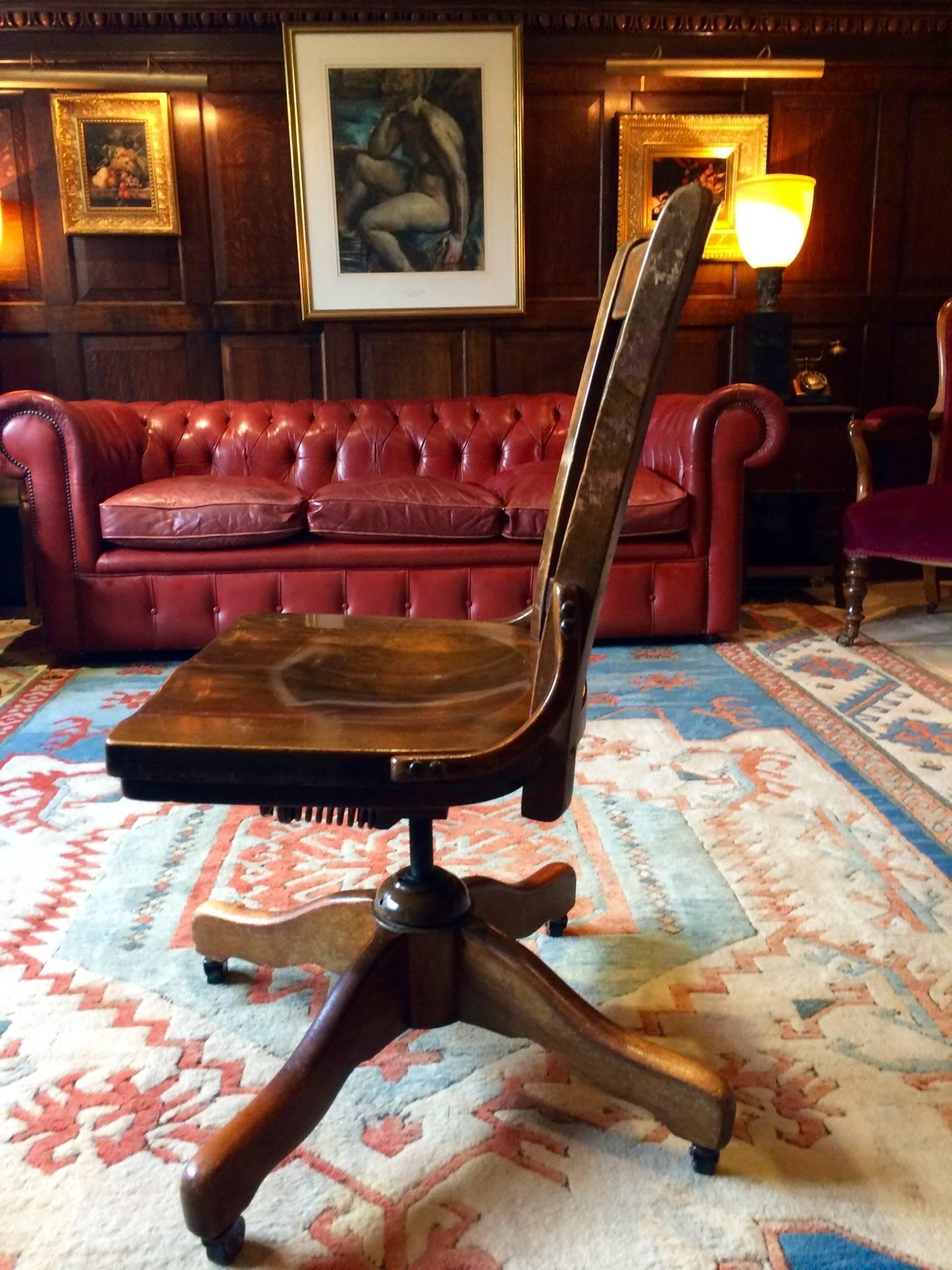 A stunning antique vintage oak rotating and reclining office chair standing on four splayed legs with casters.