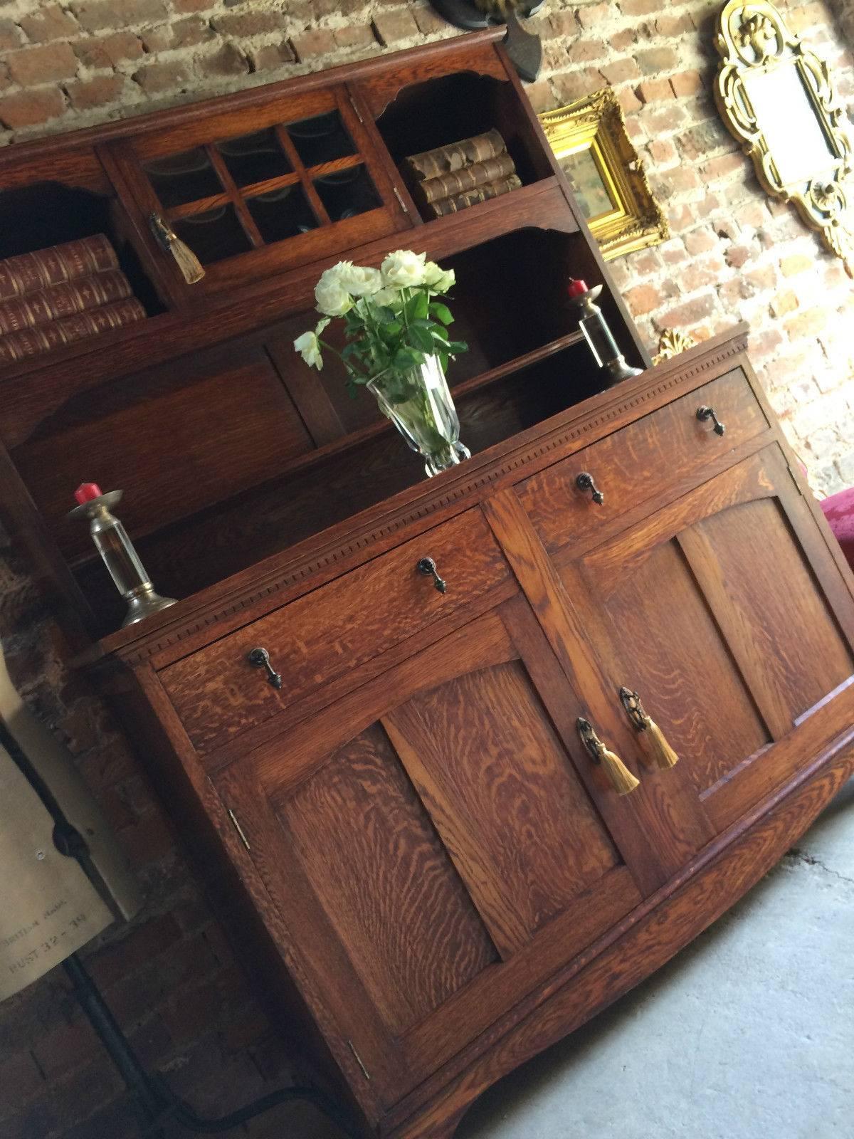 Art Nouveau cottage solid oak welsh dresser, the upper section fitted with three display shelves with central glazed cupboard above the base fitted with two drawers and two cupboards with shelves, comes with three non working keys with tassels, the