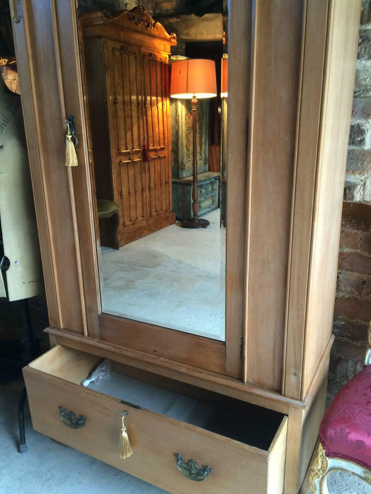 A Edwardian solid pine single door wardrobe over chest, corniced top over single beveled mirror door enclosing single hanging rail with various hooks, above single long drawer with brass handles, comes with two non working keys and tassels, please