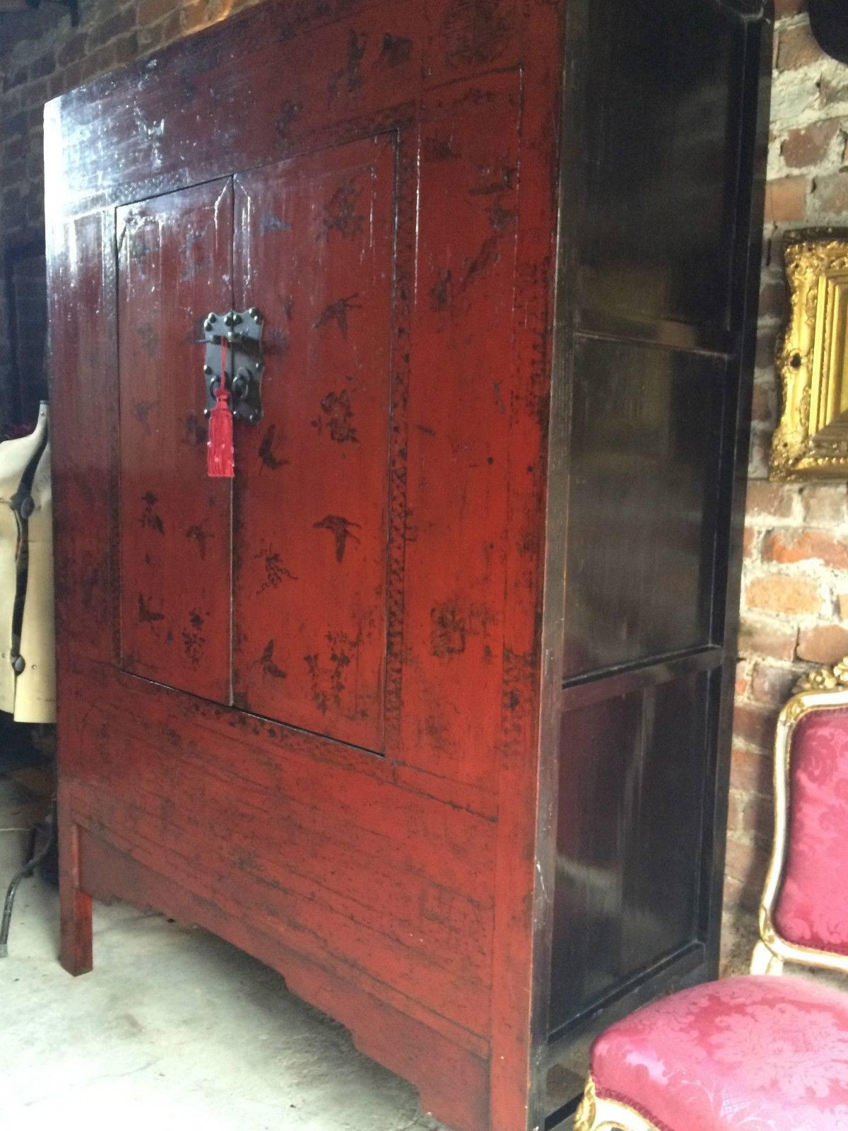 Antique 19th century elm Chinese lacquered Chinoiserie two-door wardrobe armoire, circa 1899 from the Shanxi region of China, decorated in red lacquer with flowers and butterflies, two cupboard doors with heavy large brass metalwork to front, two