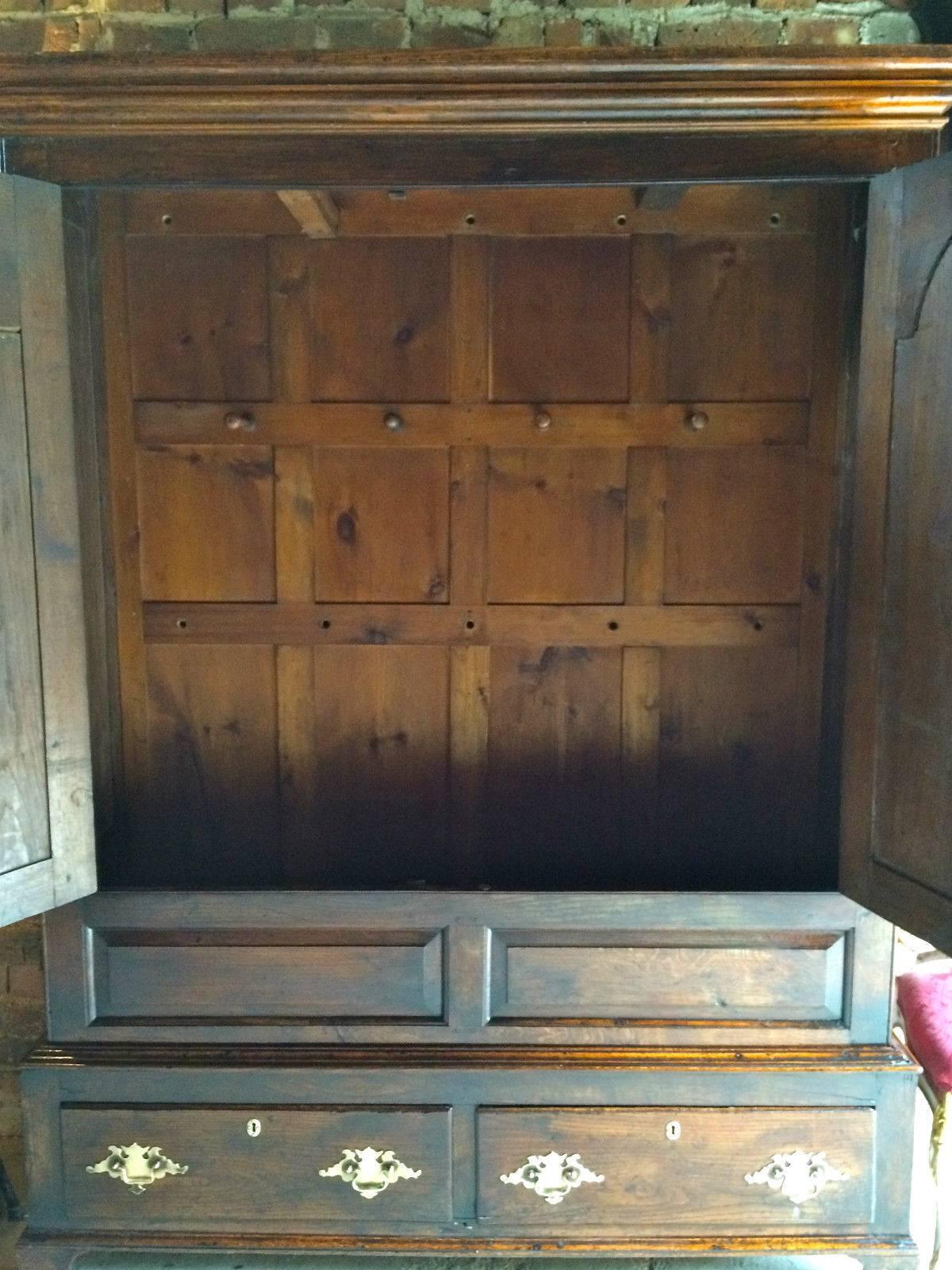 Antique George III solid oak press cupboard having a moulded cornice, fitted with two panelled doors each with arch shaped fielded panel and brass knob handles, the base fitted two short drawers both with brass drop handles and standing on bracket