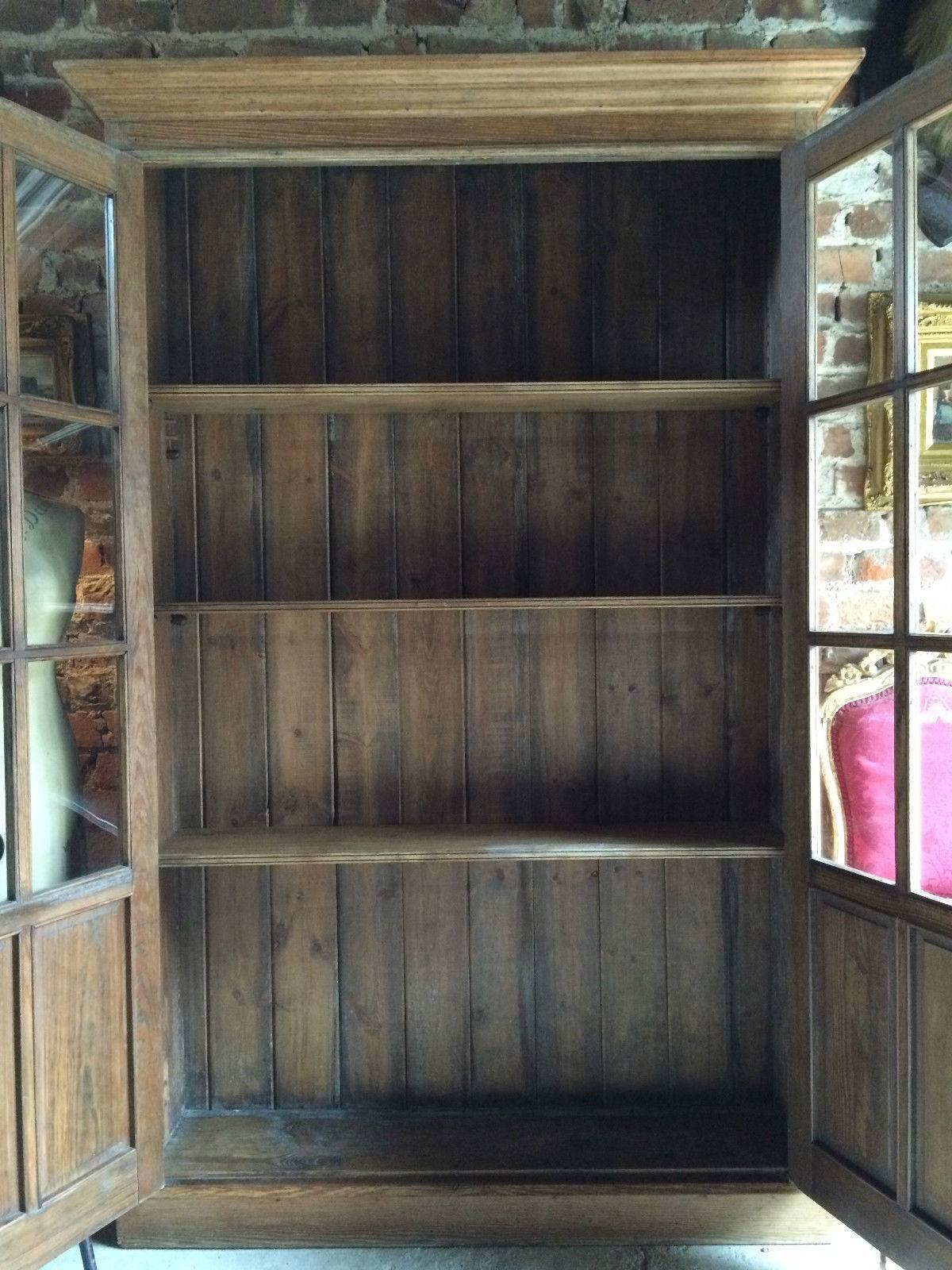 A very elegant antique solid pine two-door bookcase, two glazed doors with three adjustable shelves and standing on a plinth base, comes with one working key with tassel, please note this is a heavy piece of furniture that will require two people to