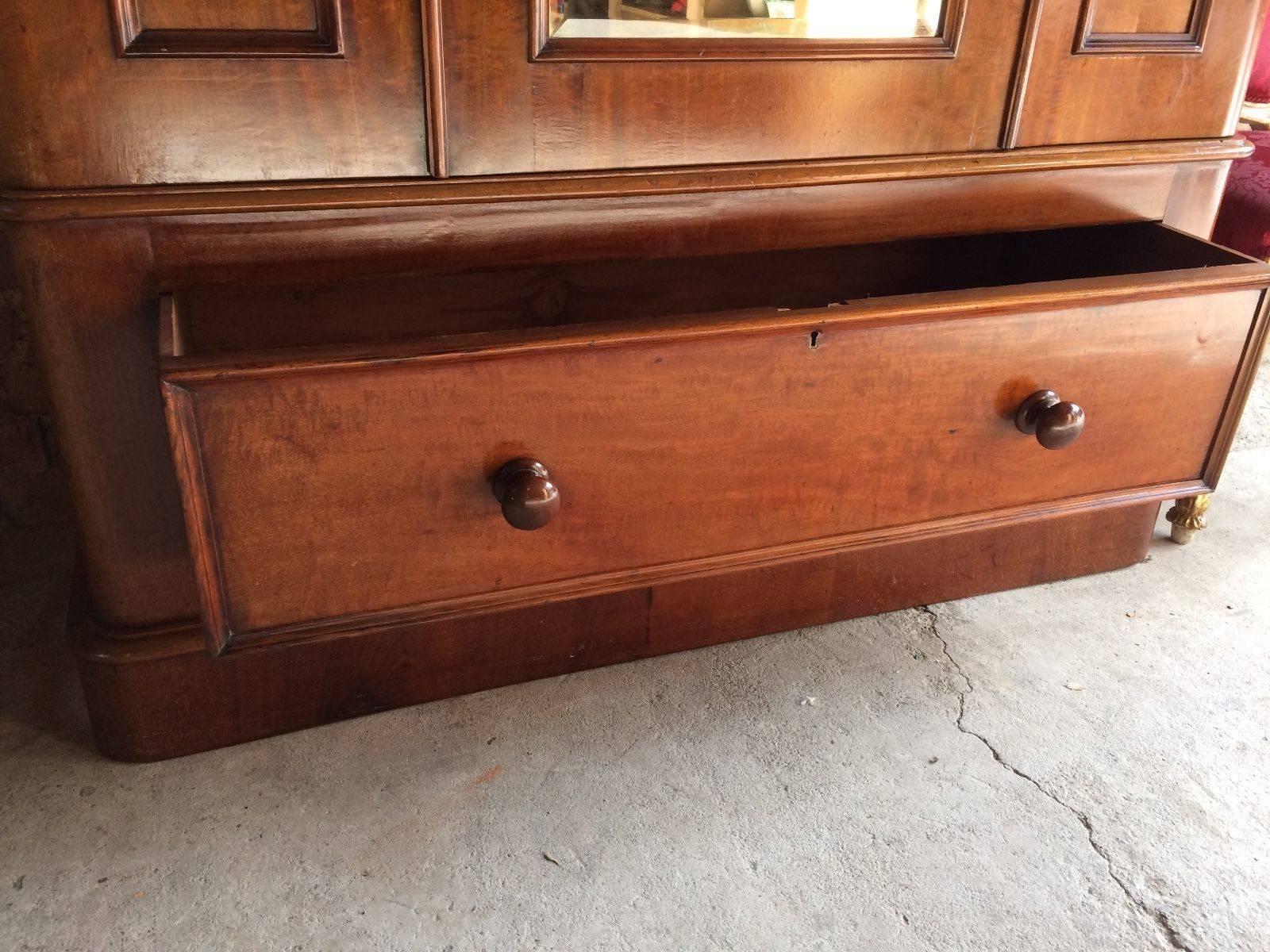 A Victorian mahogany mirror fronted wardrobe, with cornice to top over single mirror door with bevelled glass, hanging rail with hooks inside, below single pull-out double drawer with original knob handles, comes with key and tassel (non working),