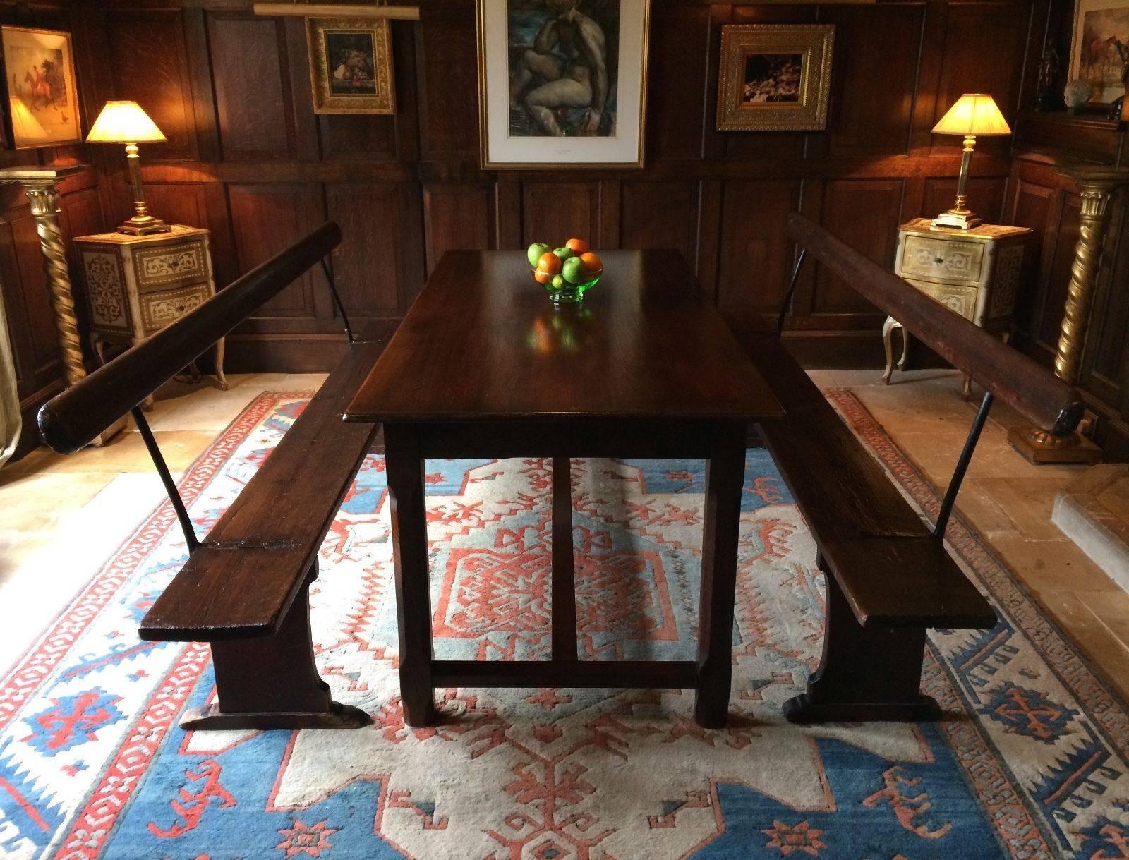 A fabulous German 'Gothic Style' stained oak refectory dining table with a pair of original early 20th century railway platform benches, seating up to ten people.